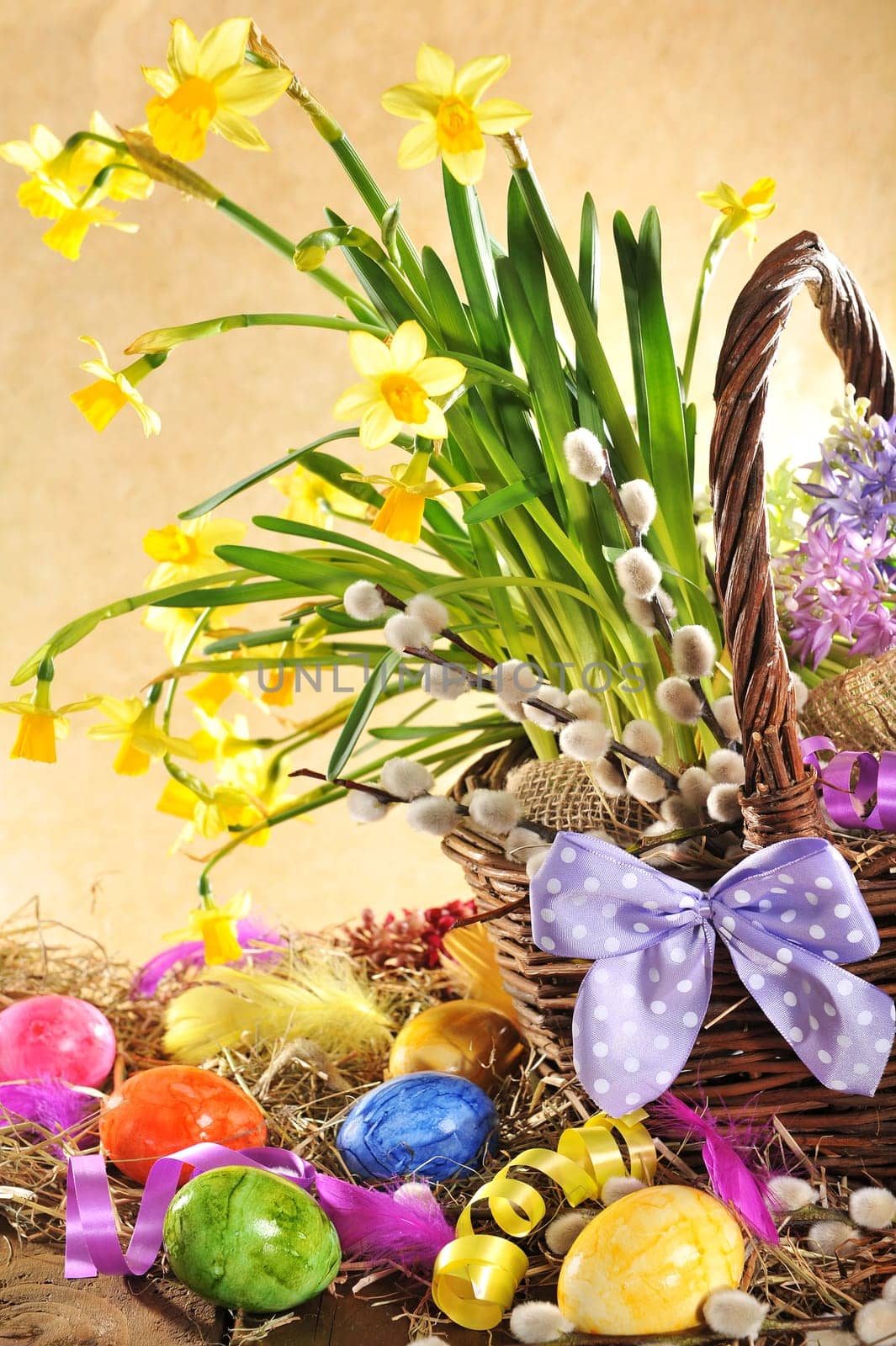 Easter basket with many daffodils and Easter eggs on old weathered wooden boards