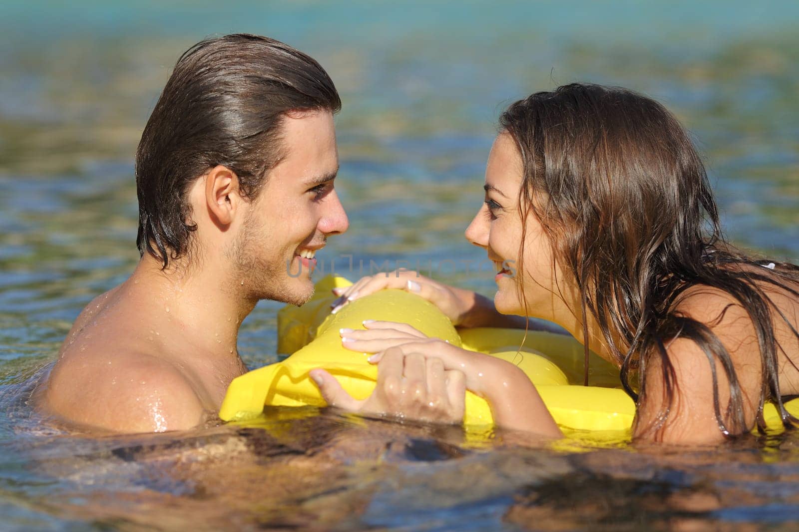 Couple in summer vacation bathing in the water of the beach and looking each other