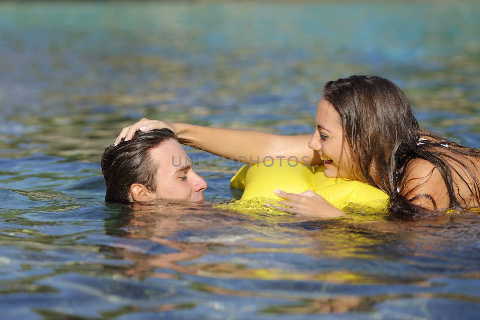 Happy couple playing on the beach in summer vacation while bathing