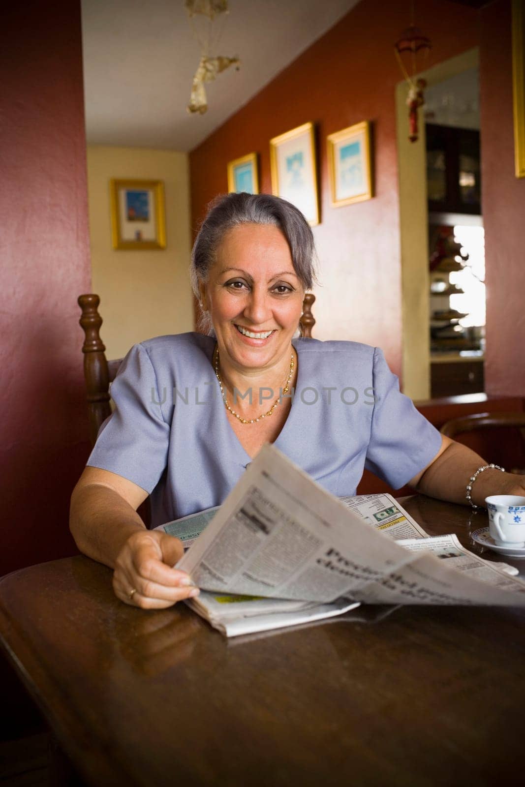 Mature woman holding a newspaper and smiling