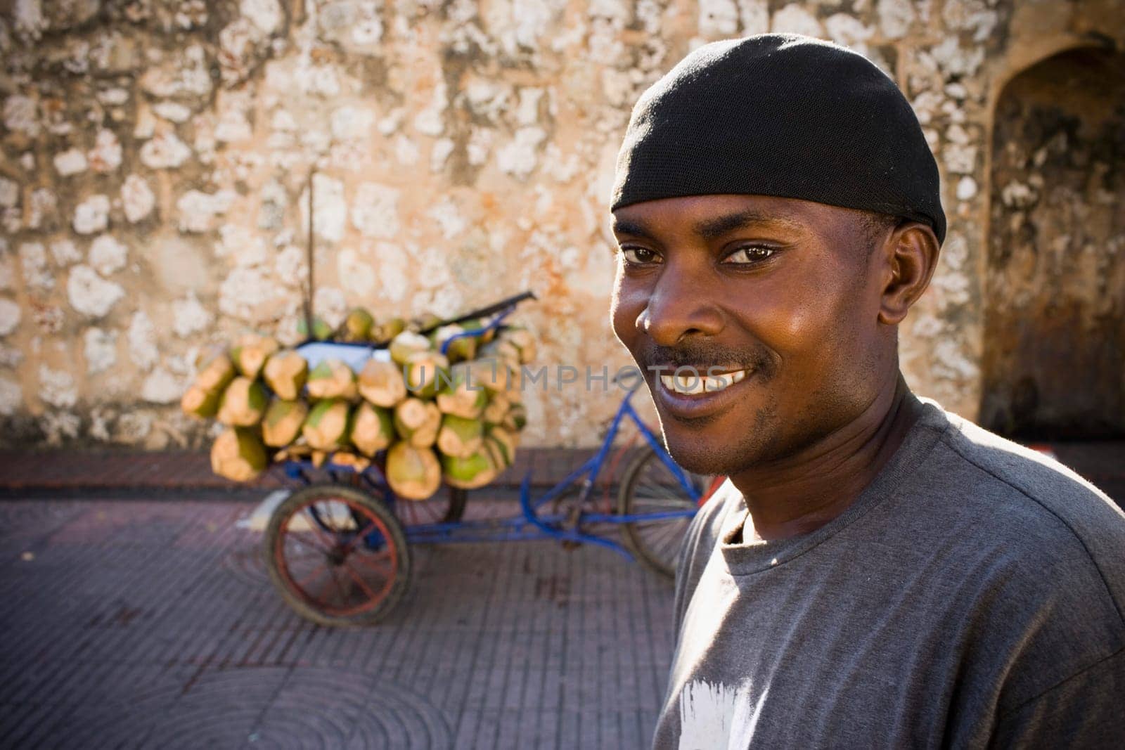 Portrait of a mid adult man smiling with coconuts on a rickshaw in the background, Santo Domingo, Dominican Republic