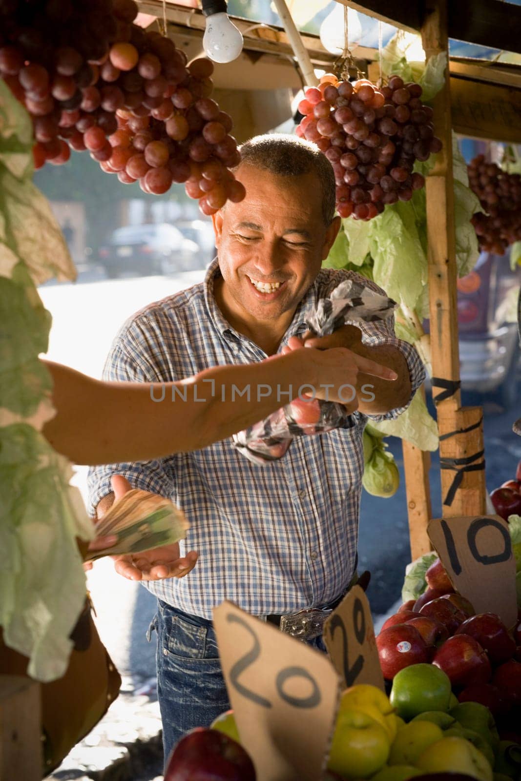 Fruit seller giving a plastic bag of fruits to a customer and holding money, Santo Domingo, Dominican Republic