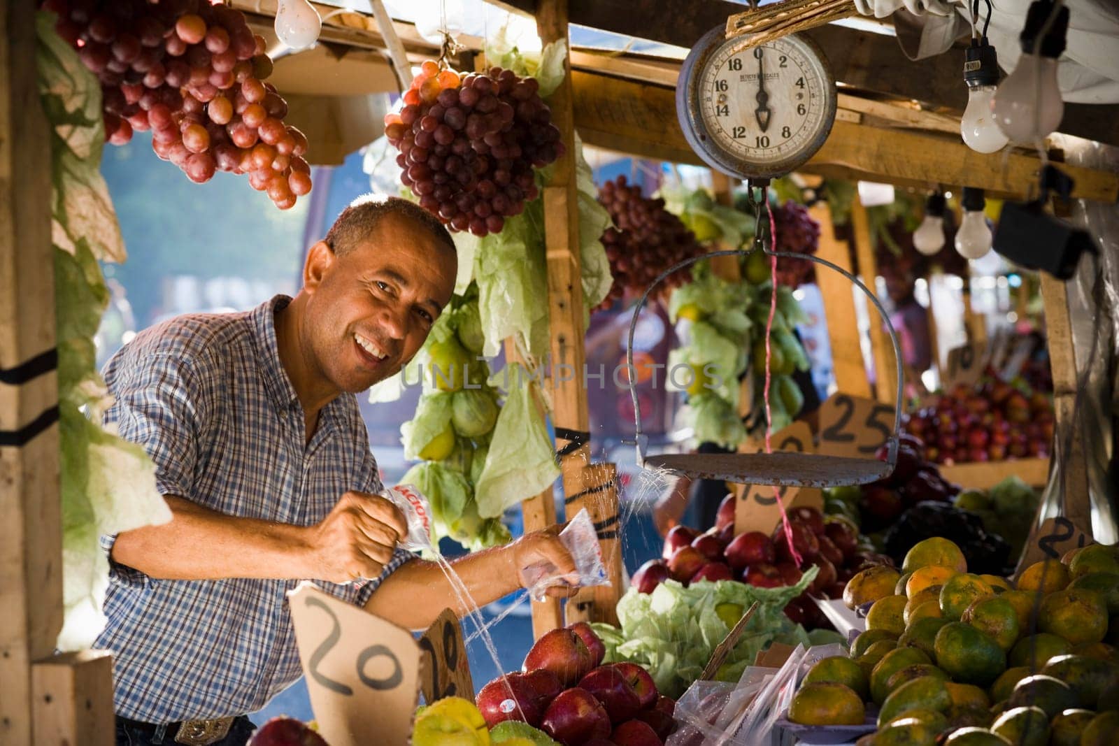 Portrait of a fruit seller splashing water over fruits at a market stall, Santo Domingo, Dominican Republic