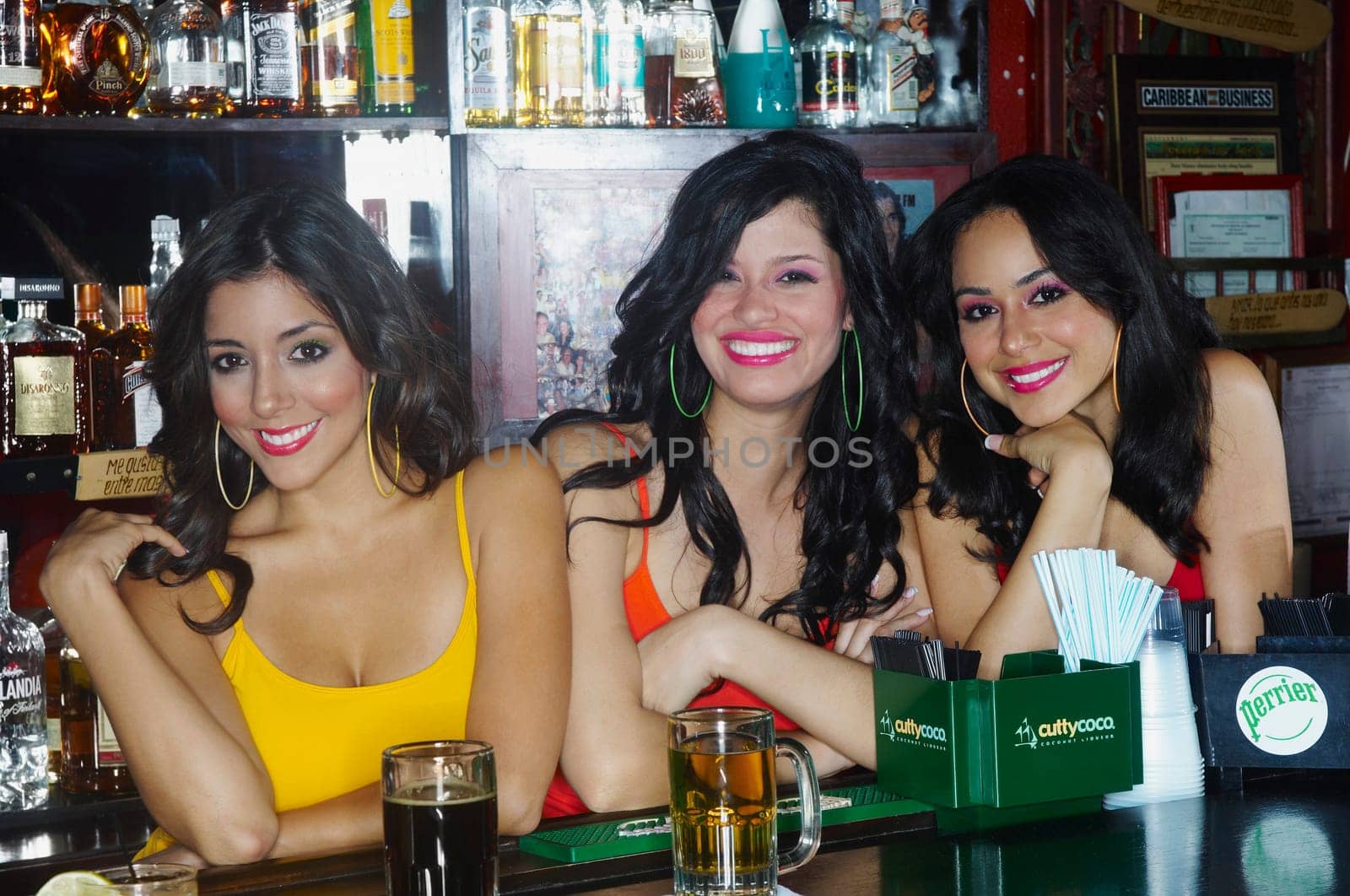 Three sexy young waitresses serve drinks behind bar