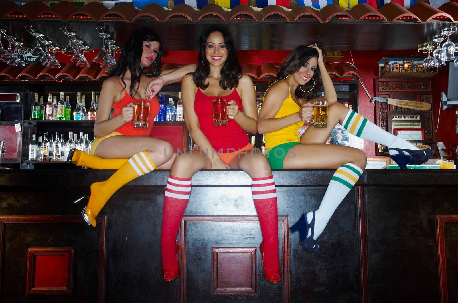 Three sexy young waitresses sitting on bar counter