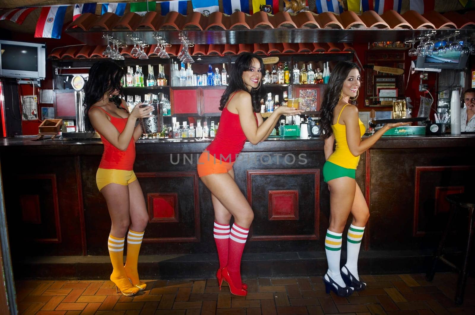 Three sexy young waitresses standing in front of bar counter