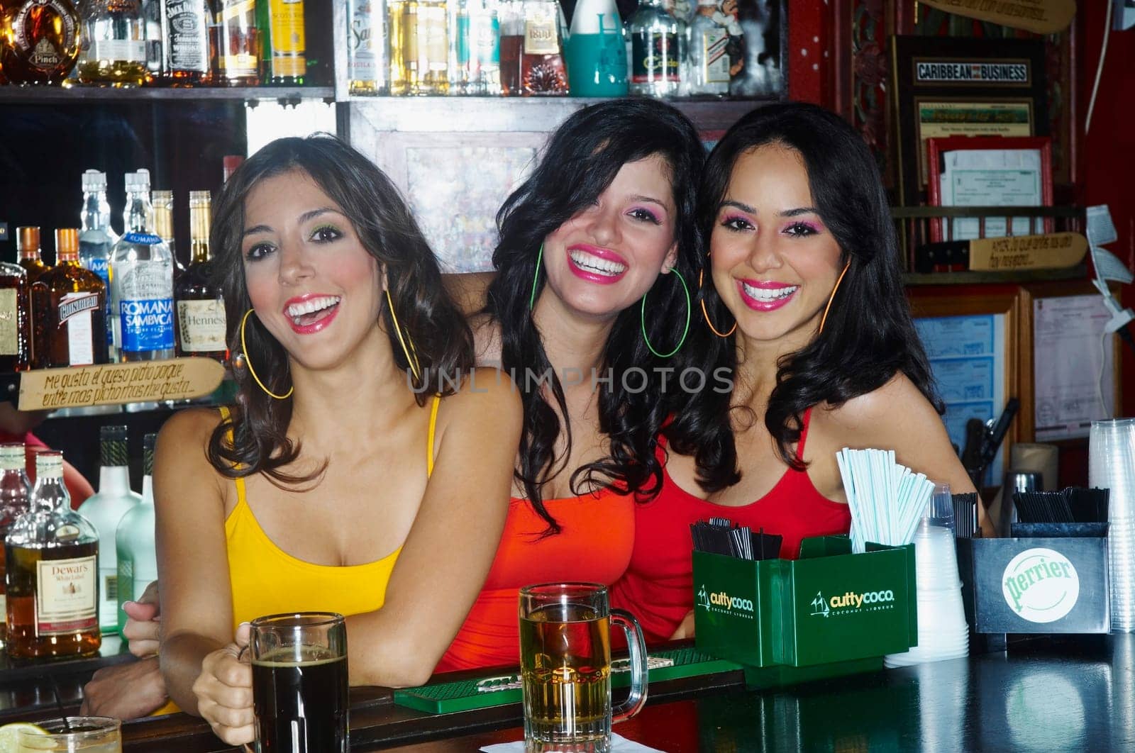 Three sexy young waitresses serve drinks behind bar