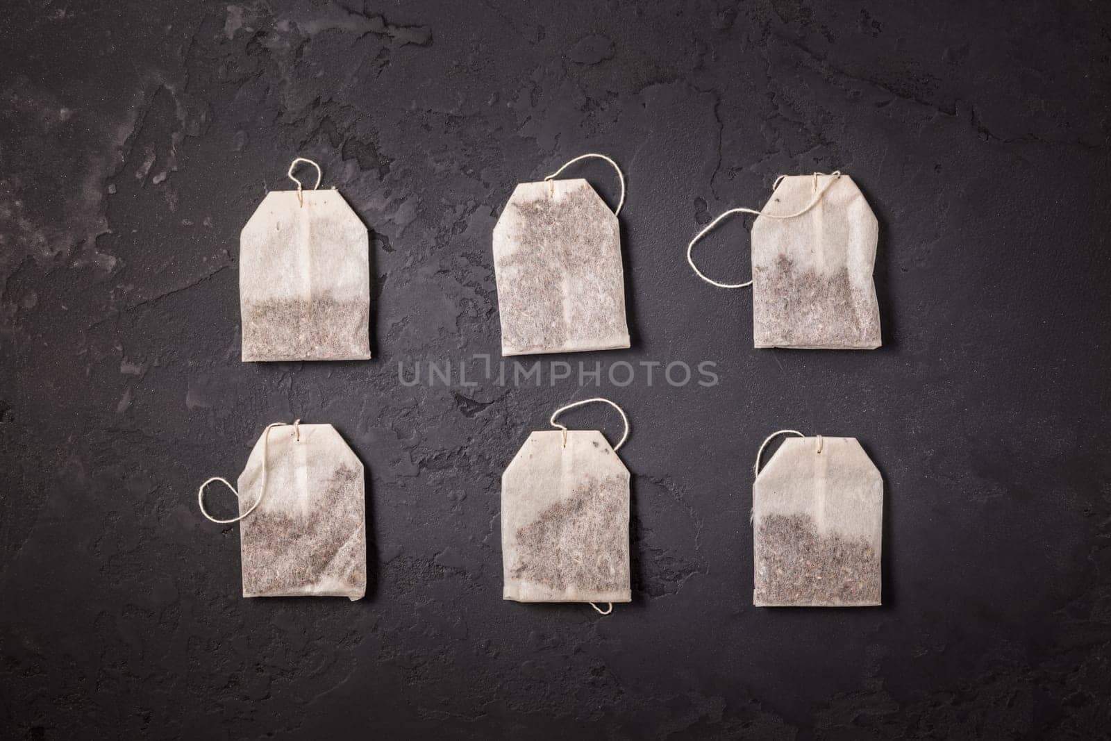 Assorted tea bags on black stone background