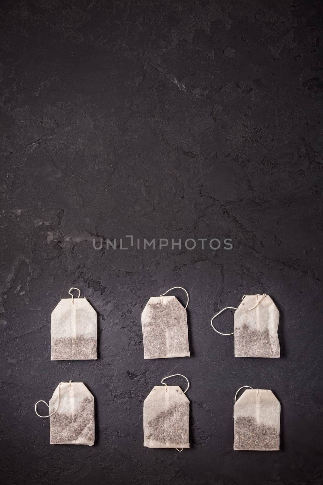 Assorted tea bags on black stone background