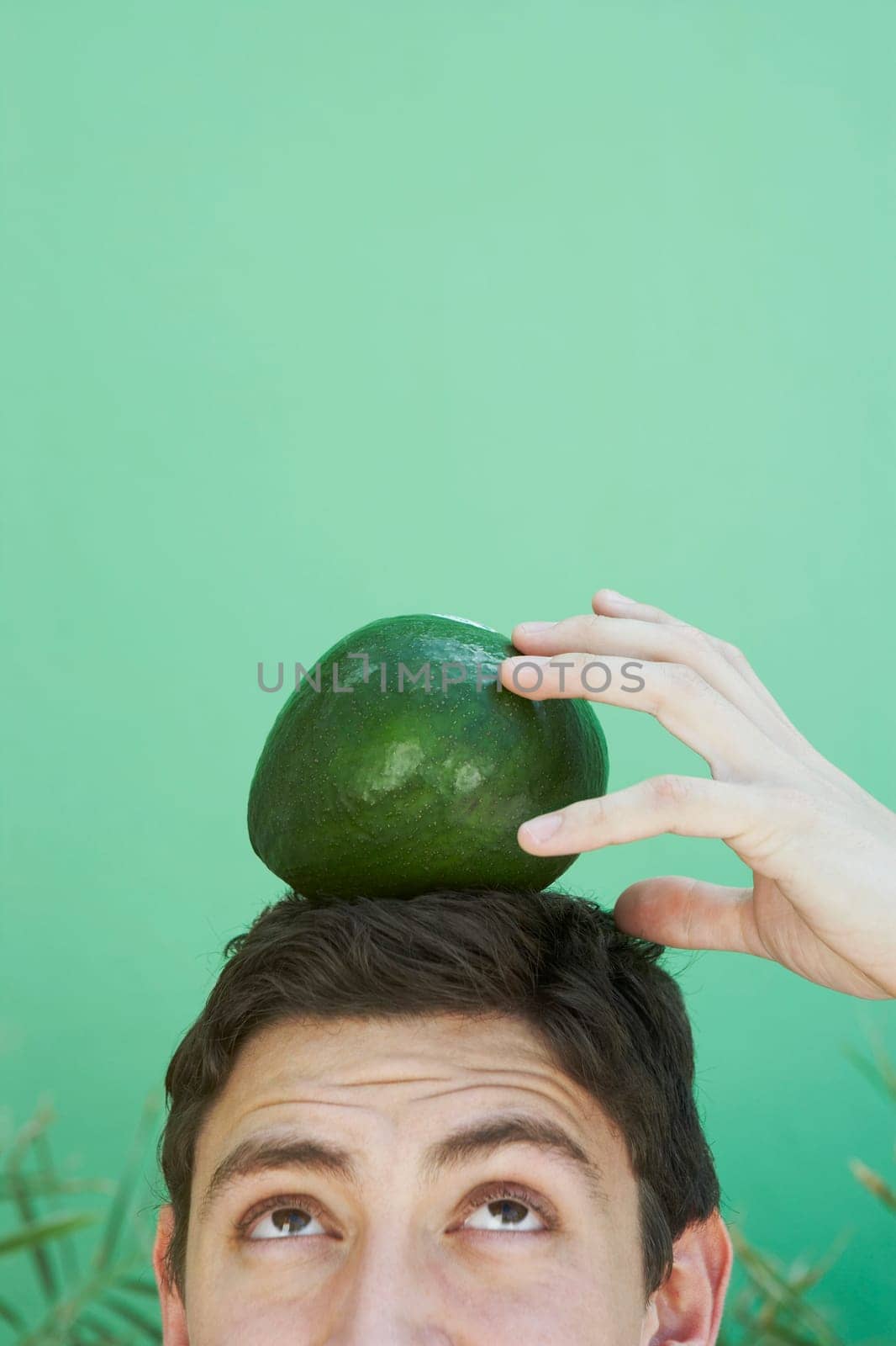 Young man balancing an avocado on his head