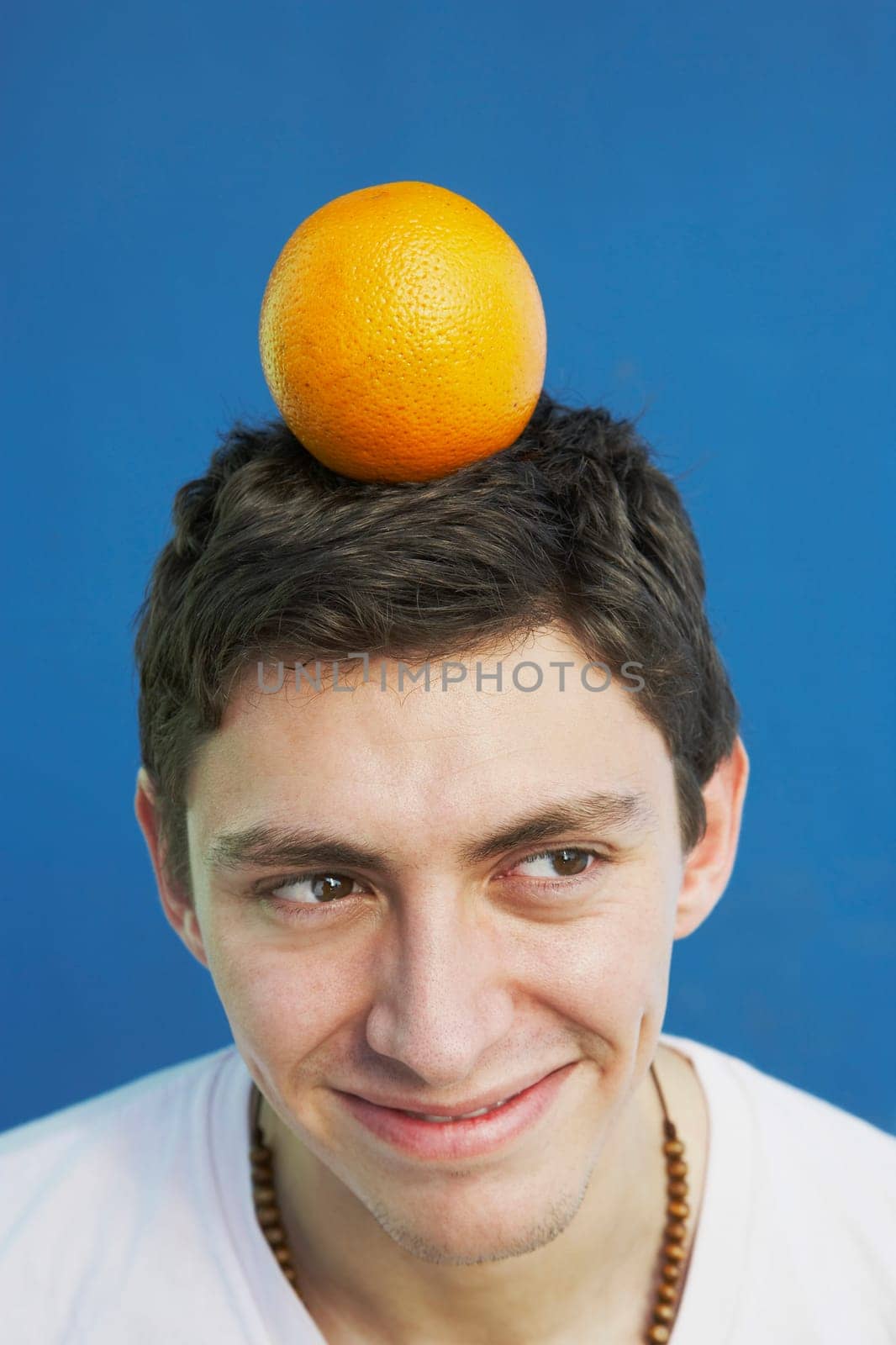 Young man balancing an orange on his head