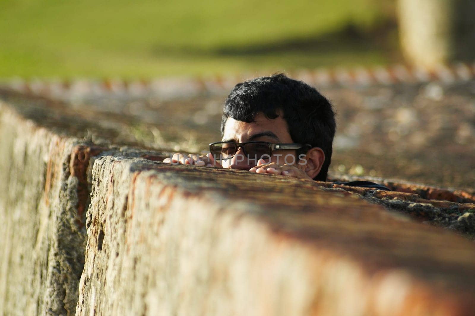 Young man peeking over fence