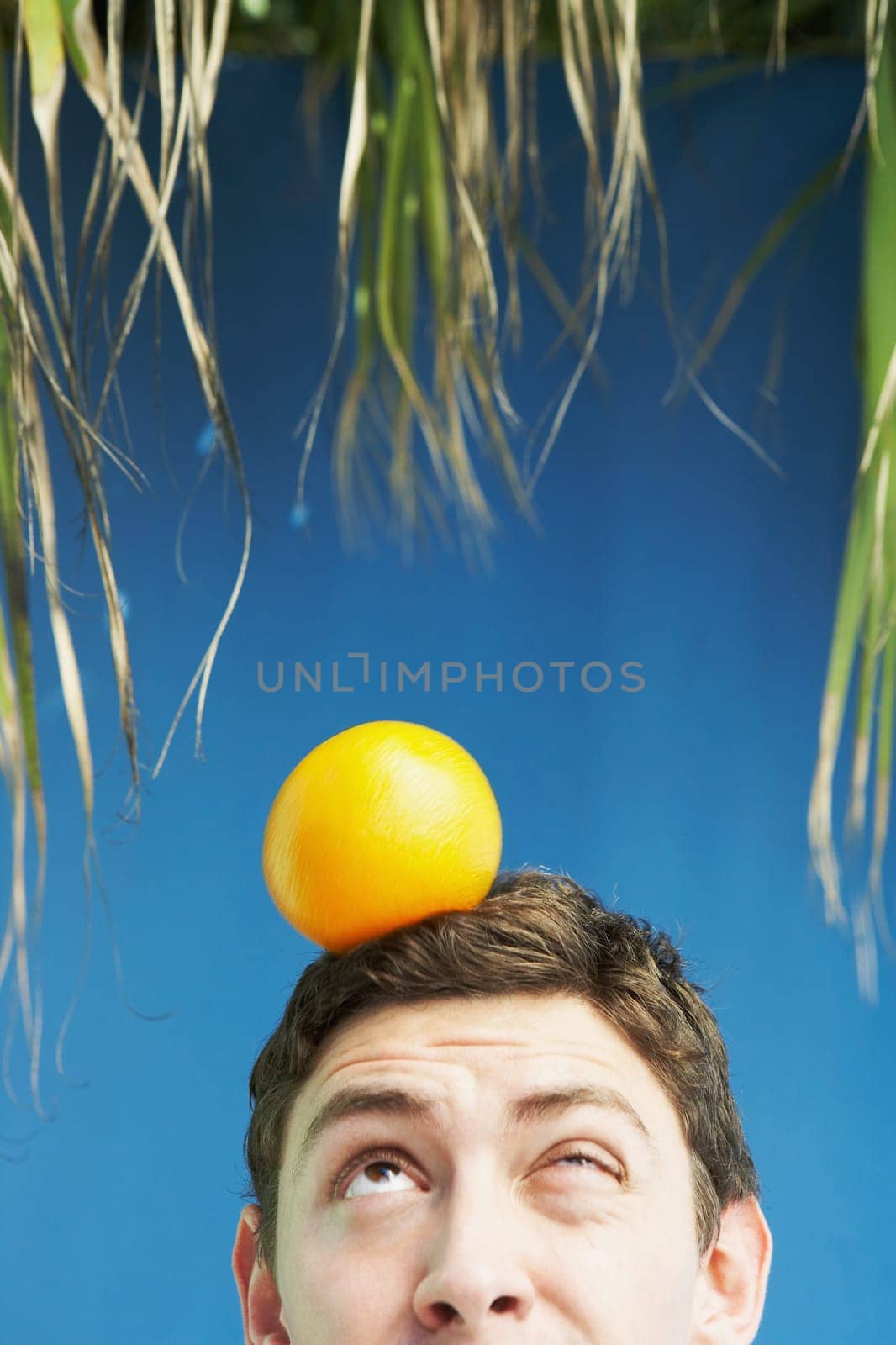 Young man balancing an orange on his head