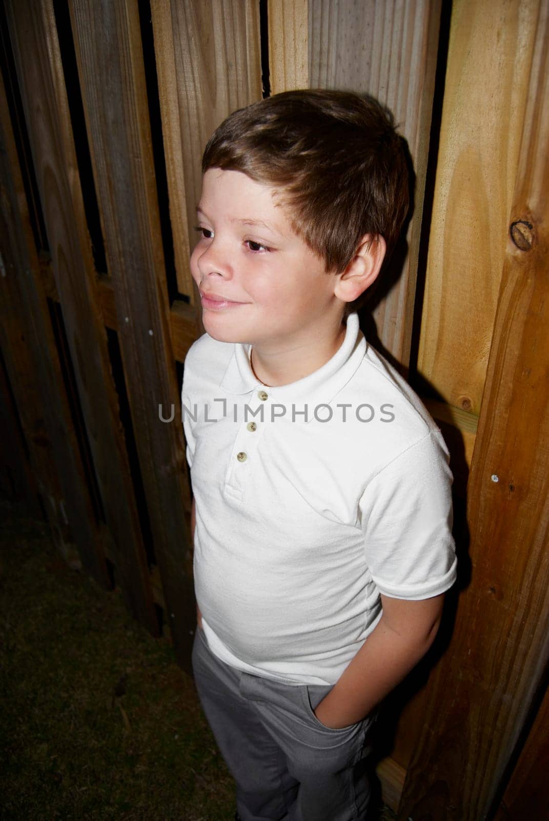 Young boy standing by fence