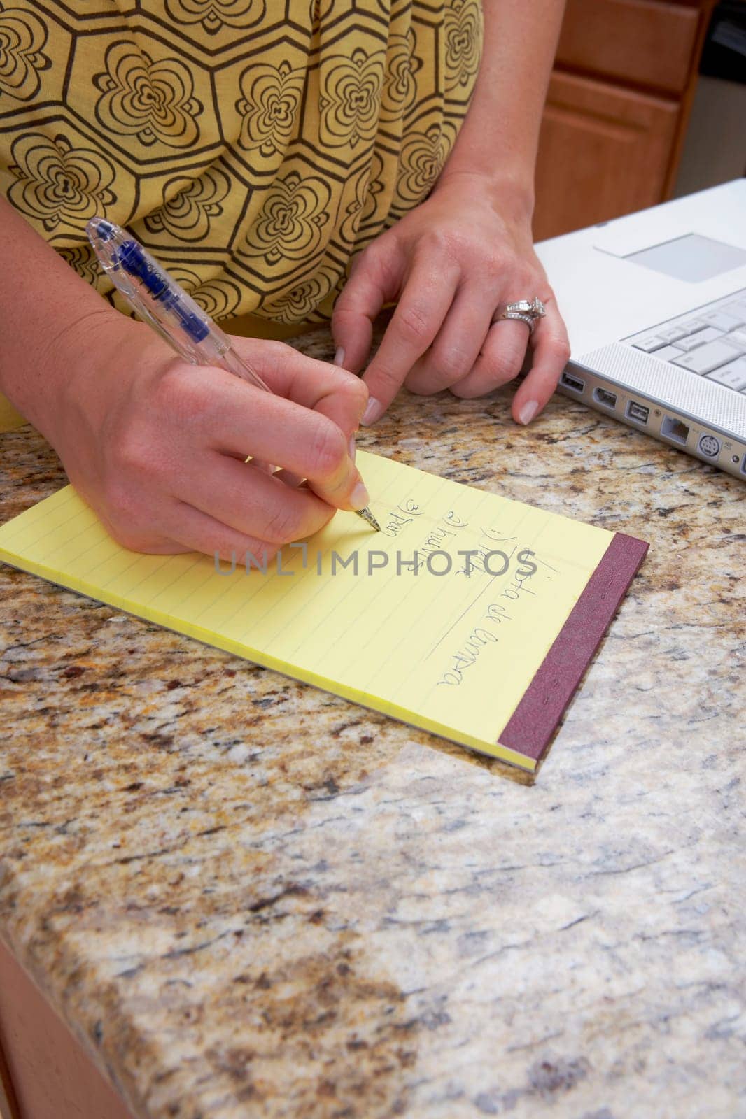 Mid section view of a woman writing on a notepad