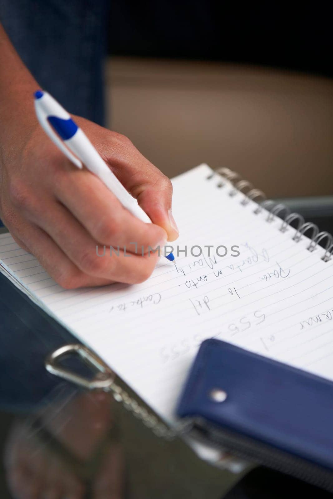 Close-up of a man's hand writing on a spiral notebook