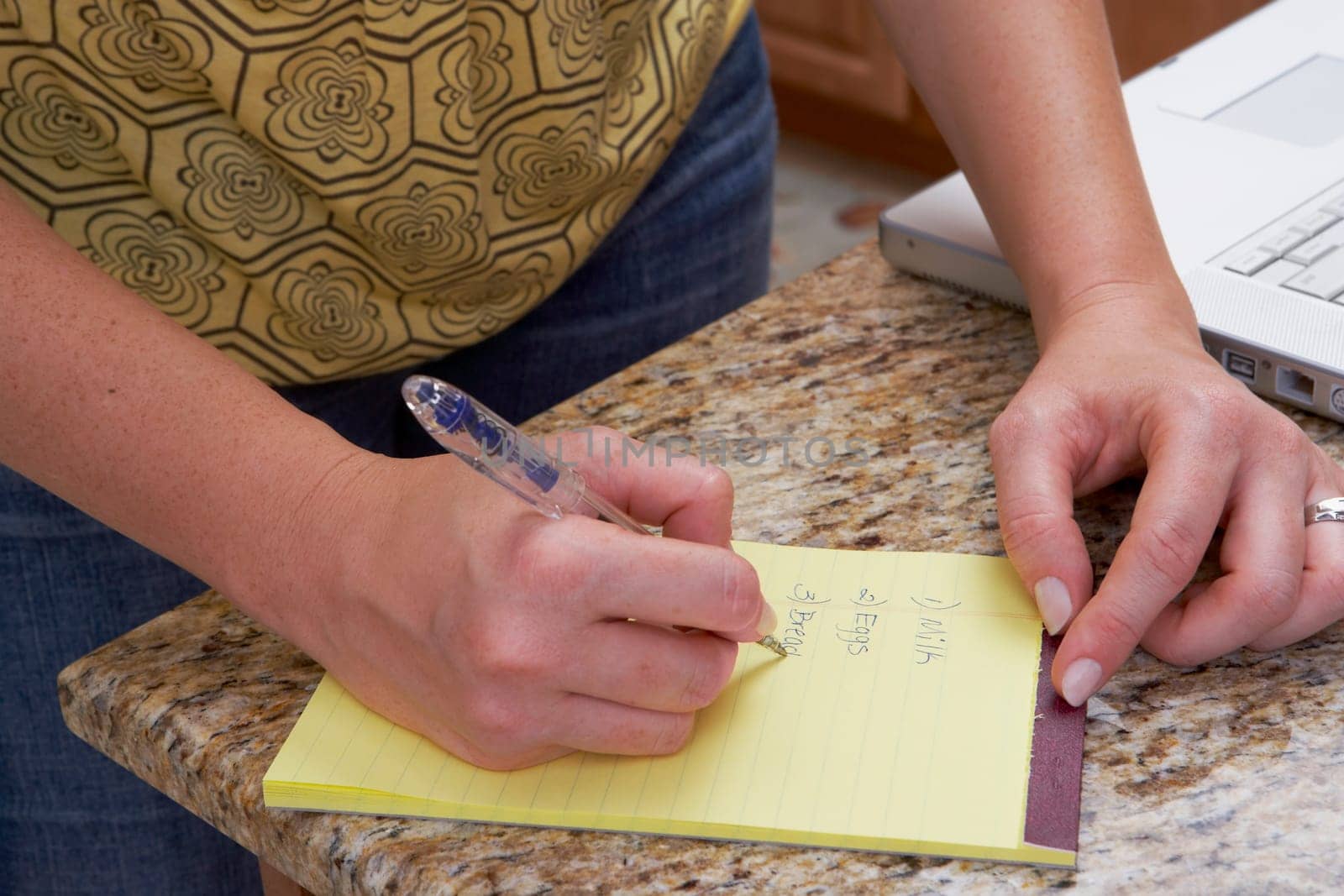 Mid section view of a woman writing on a notepad