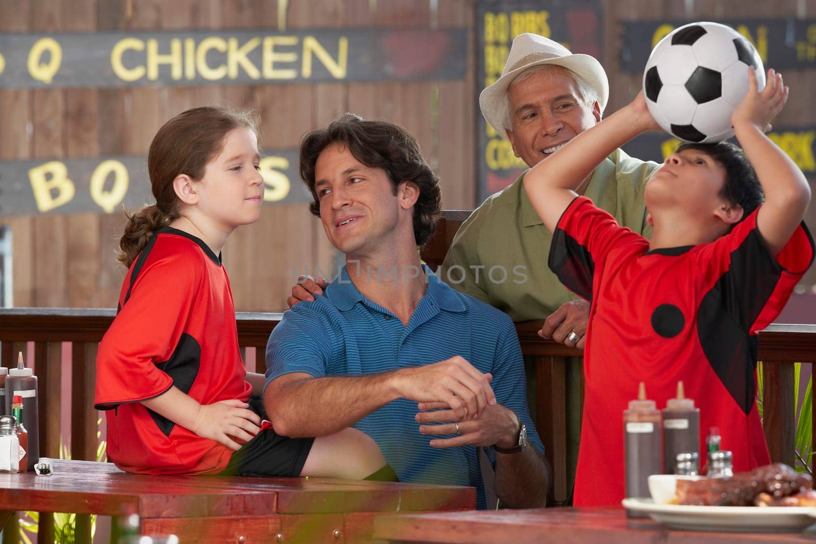 Boy playing with a soccer ball with his family beside him in a restaurant
