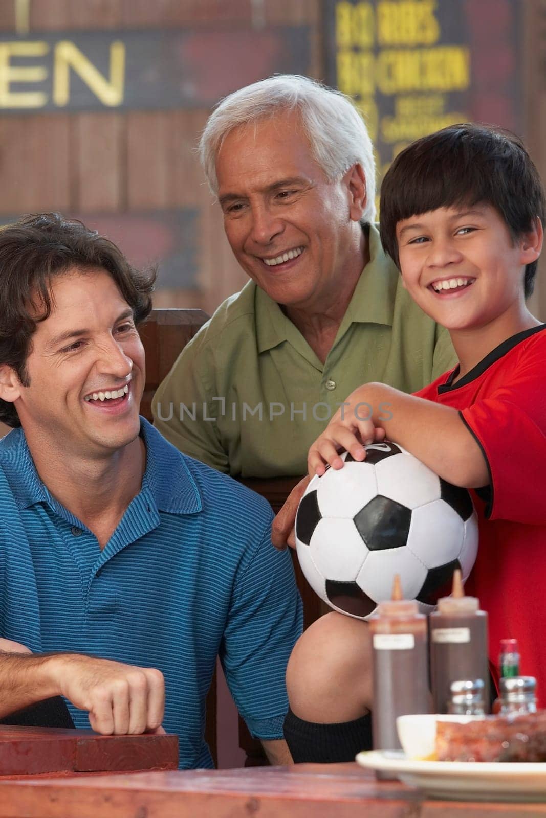 Senior man with his son and grandson sitting in a restaurant and smiling