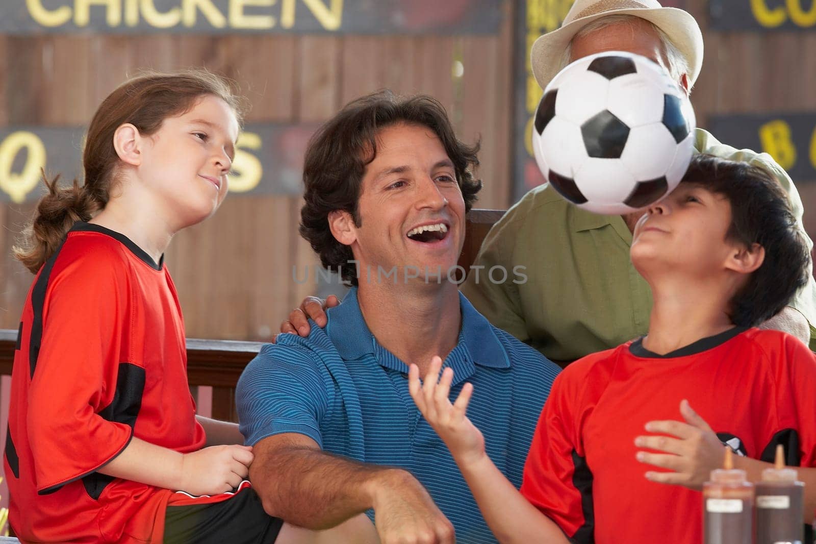 Boy playing with a soccer ball with his family looking at him in a restaurant