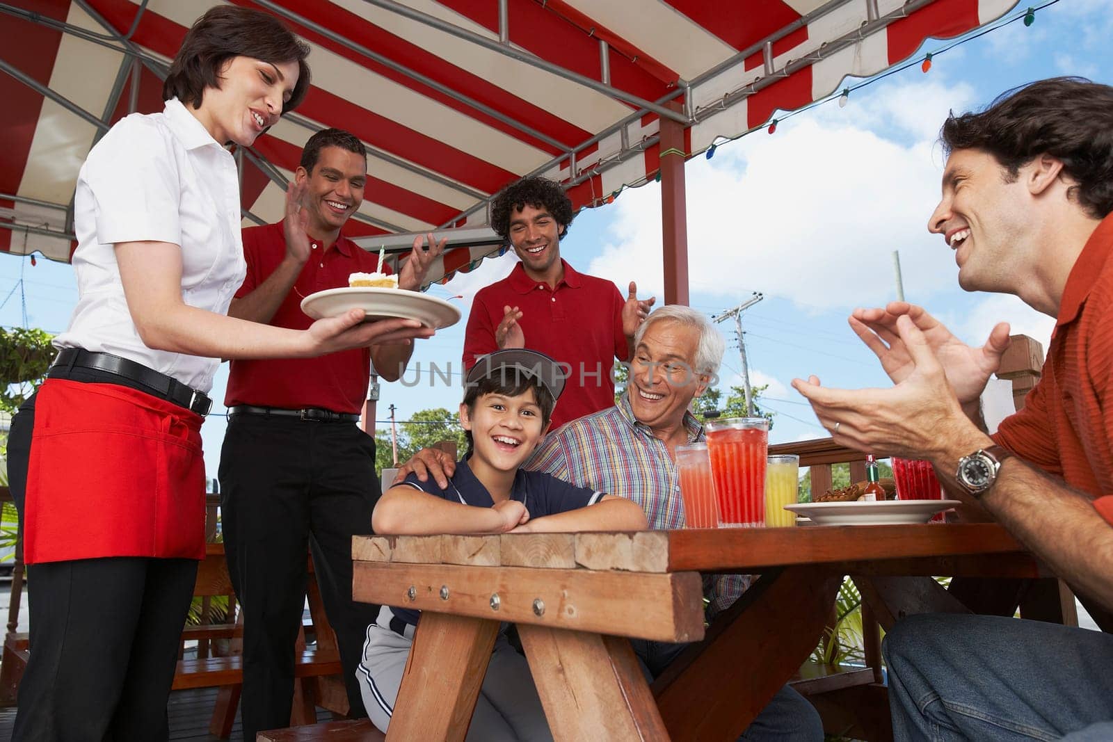 Boy celebrating his birthday with his father and grandfather in a restaurant