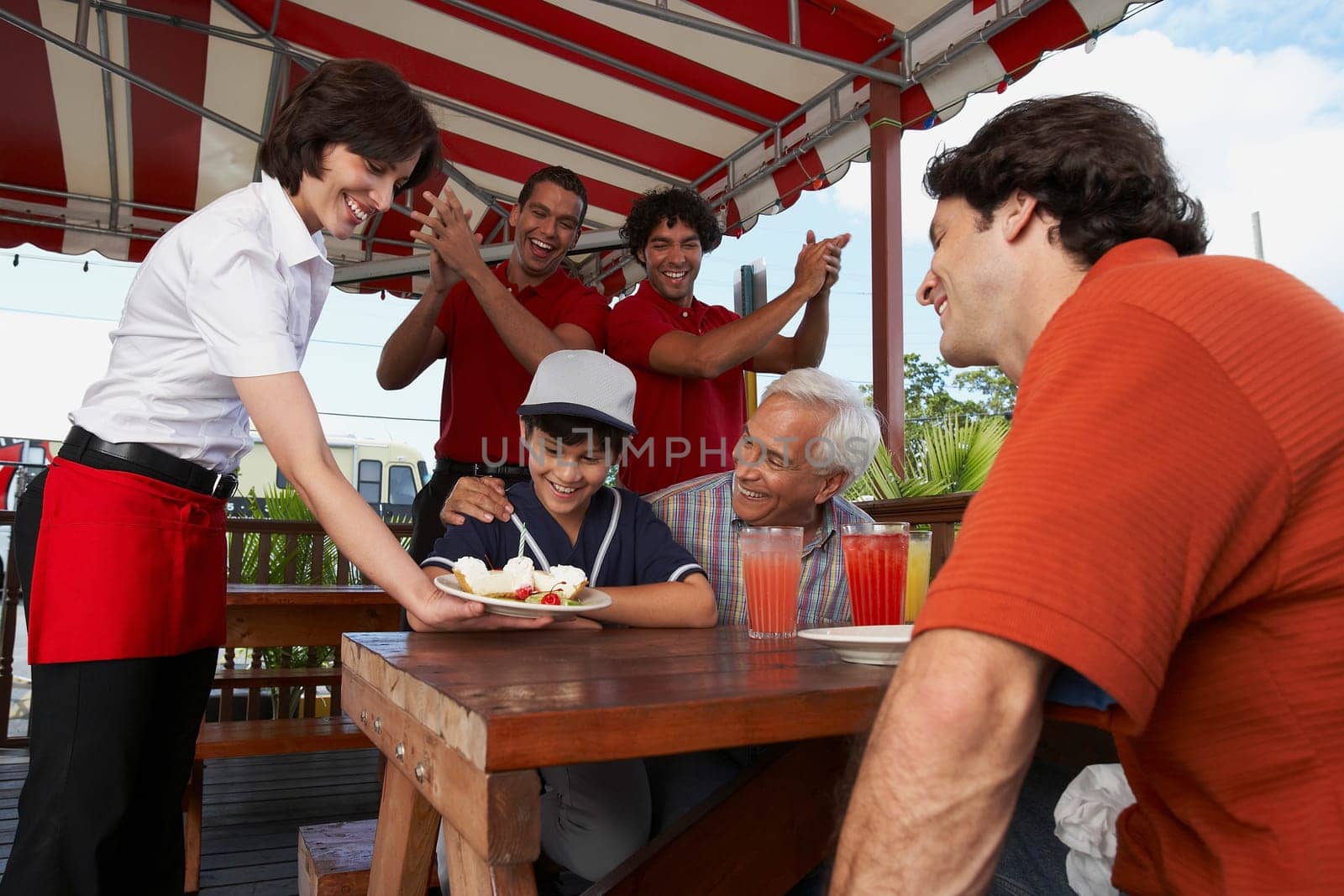 Boy celebrating his birthday with his father and grandfather in a restaurant