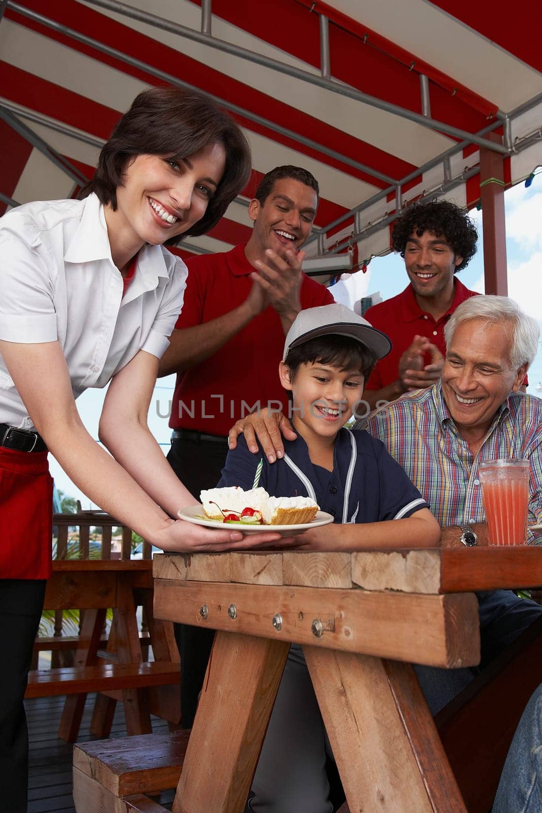Portrait of a young woman serving dessert to a boy celebrating his birthday in a restaurant