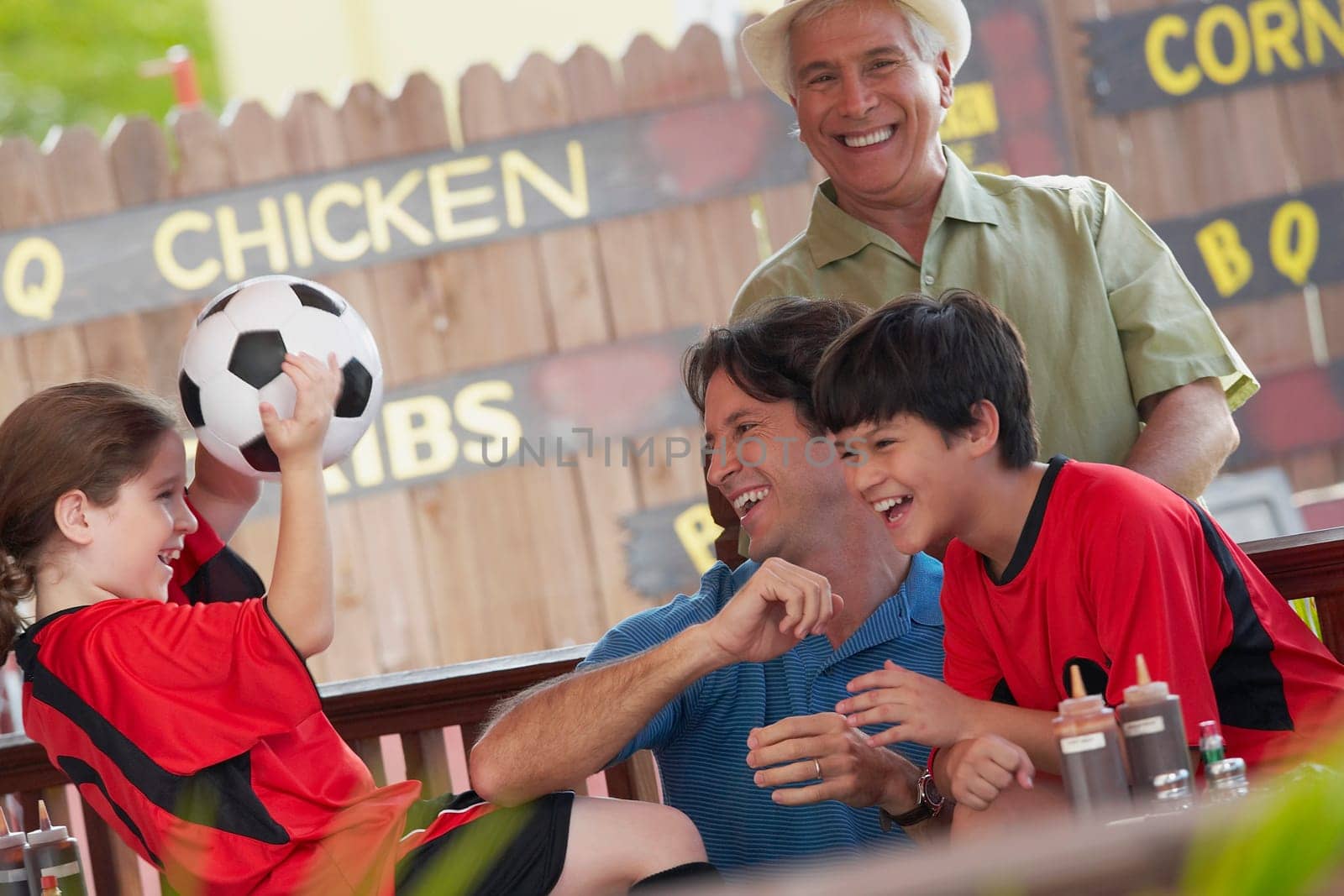 Mid adult man playing with his children in a restaurant and his father standing behind him
