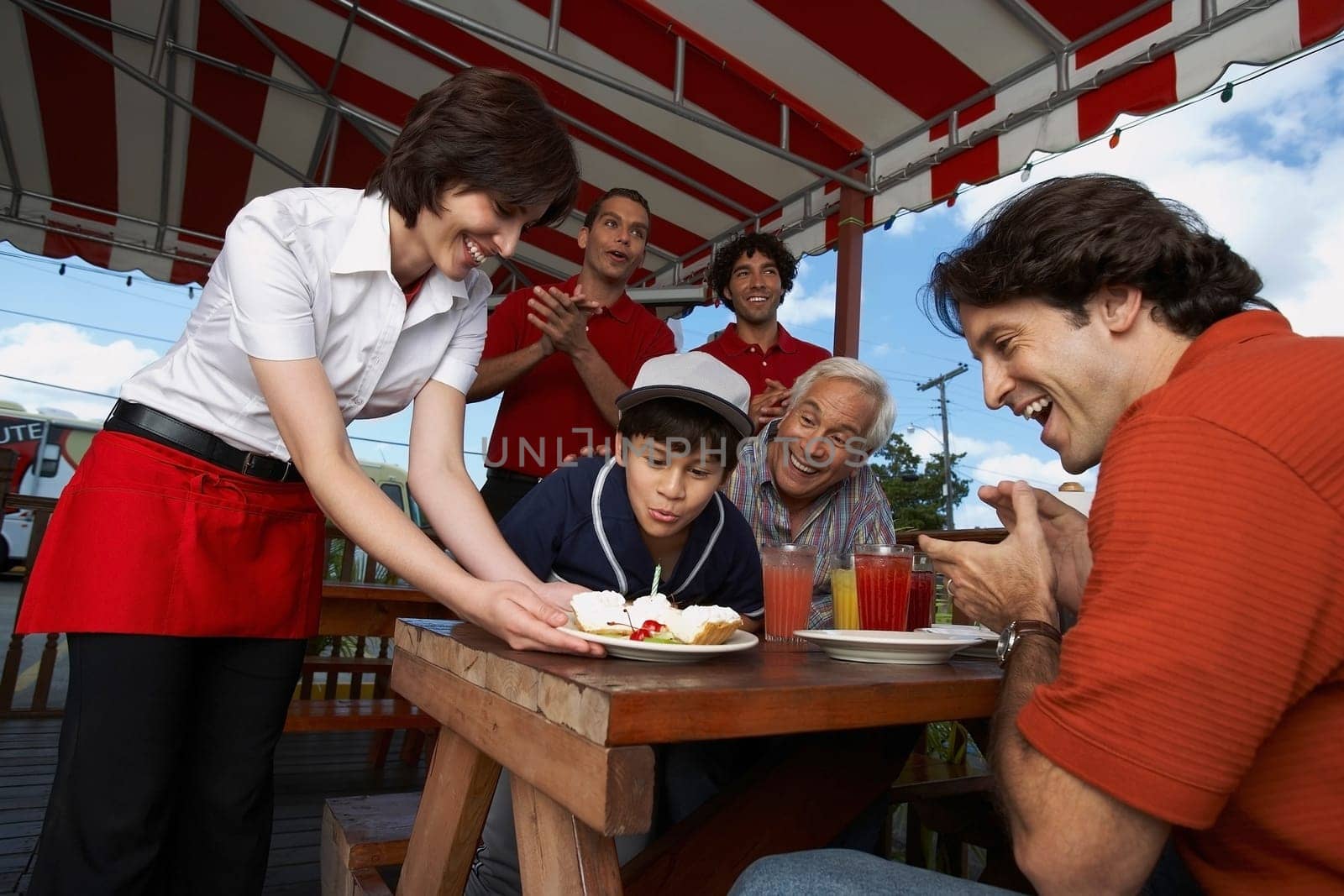 Boy celebrating his birthday with his father and grandfather in a restaurant