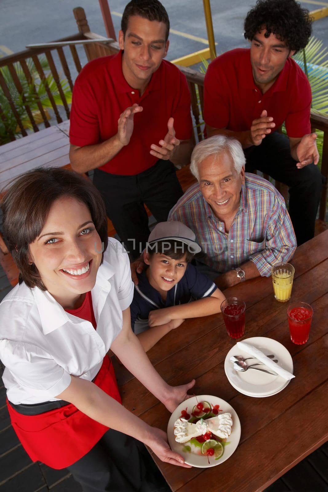 Portrait of a young woman serving dessert to a boy celebrating his birthday in a restaurant