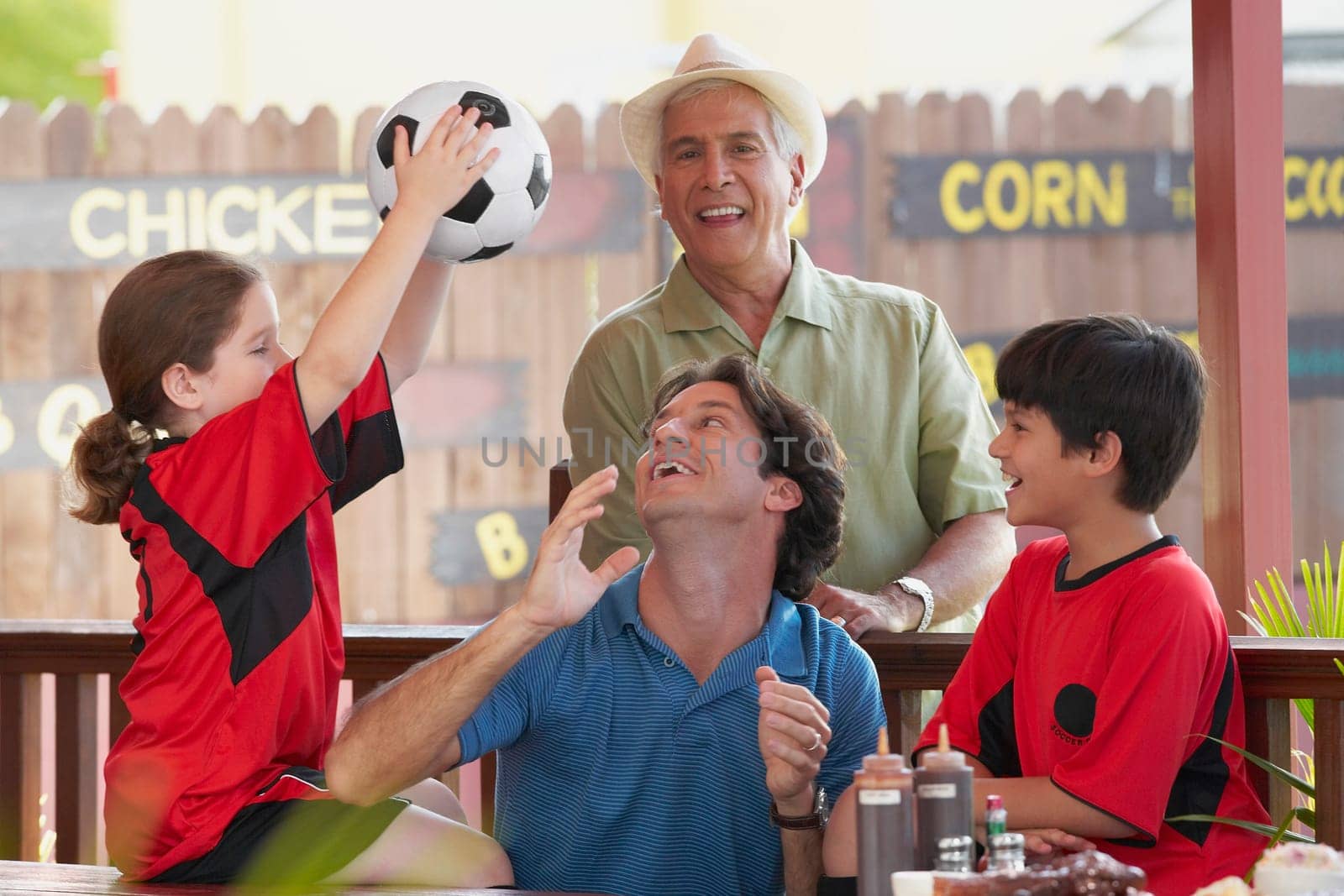 Mid adult man playing with his children in a restaurant with his father standing behind him