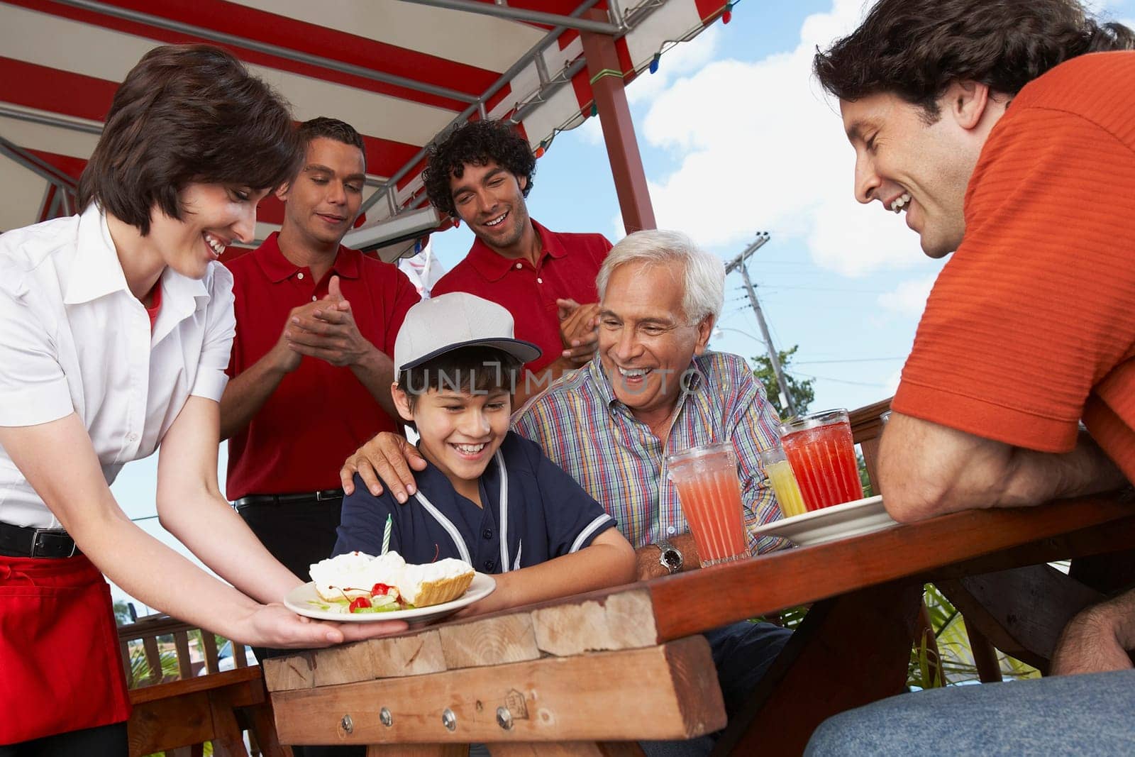 Boy celebrating his birthday with his father and grandfather in a restaurant