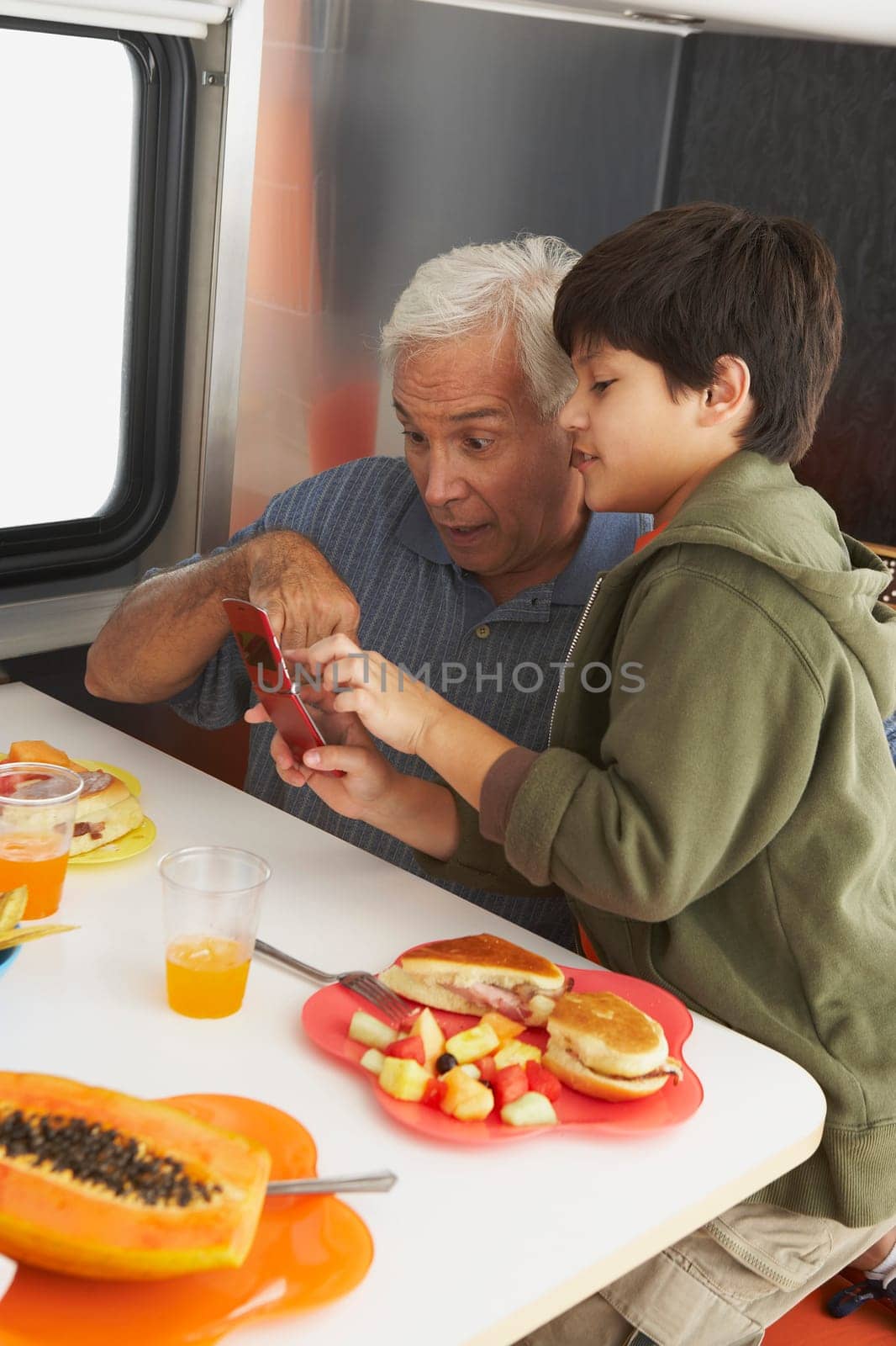Side profile of a boy teaching his grandfather how to use a mobile phone