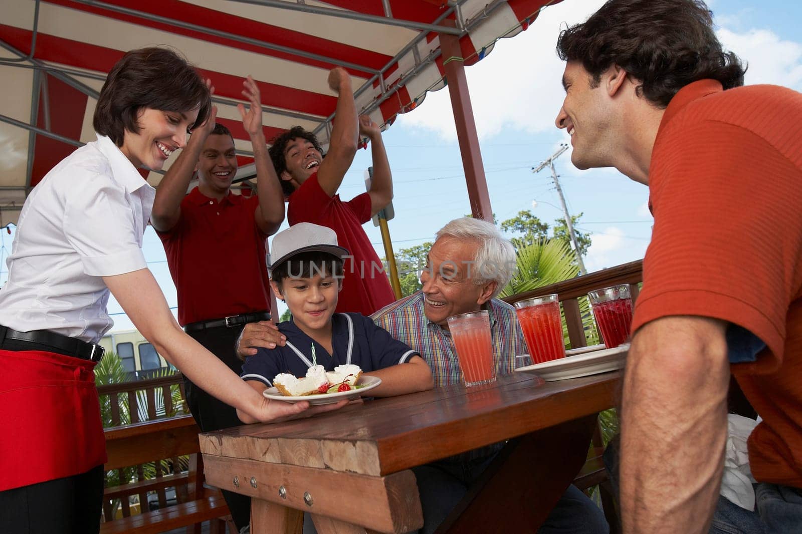 Boy celebrating his birthday with his father and grandfather in a restaurant