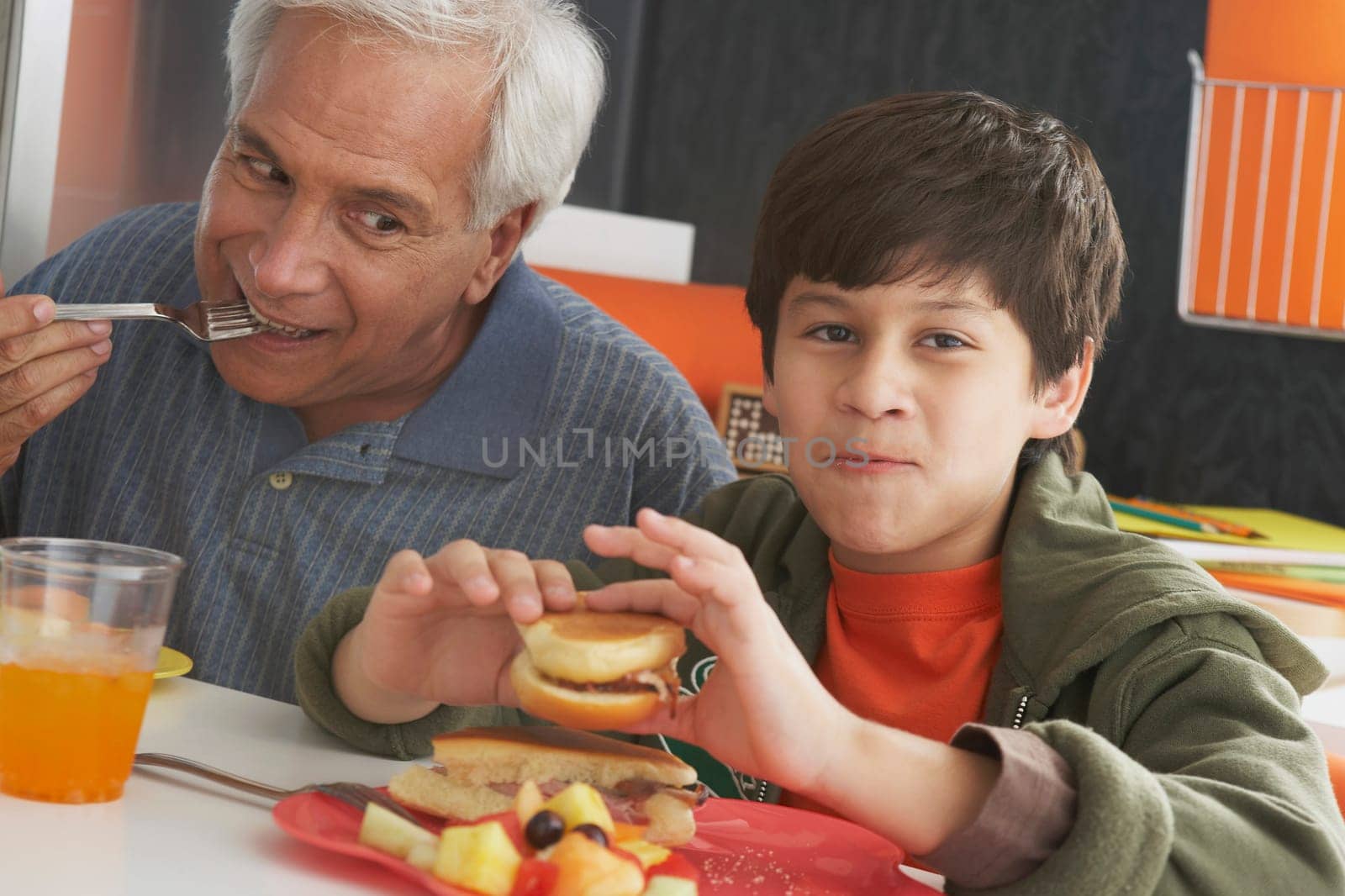 Senior man with his grandson having meal at the dining table
