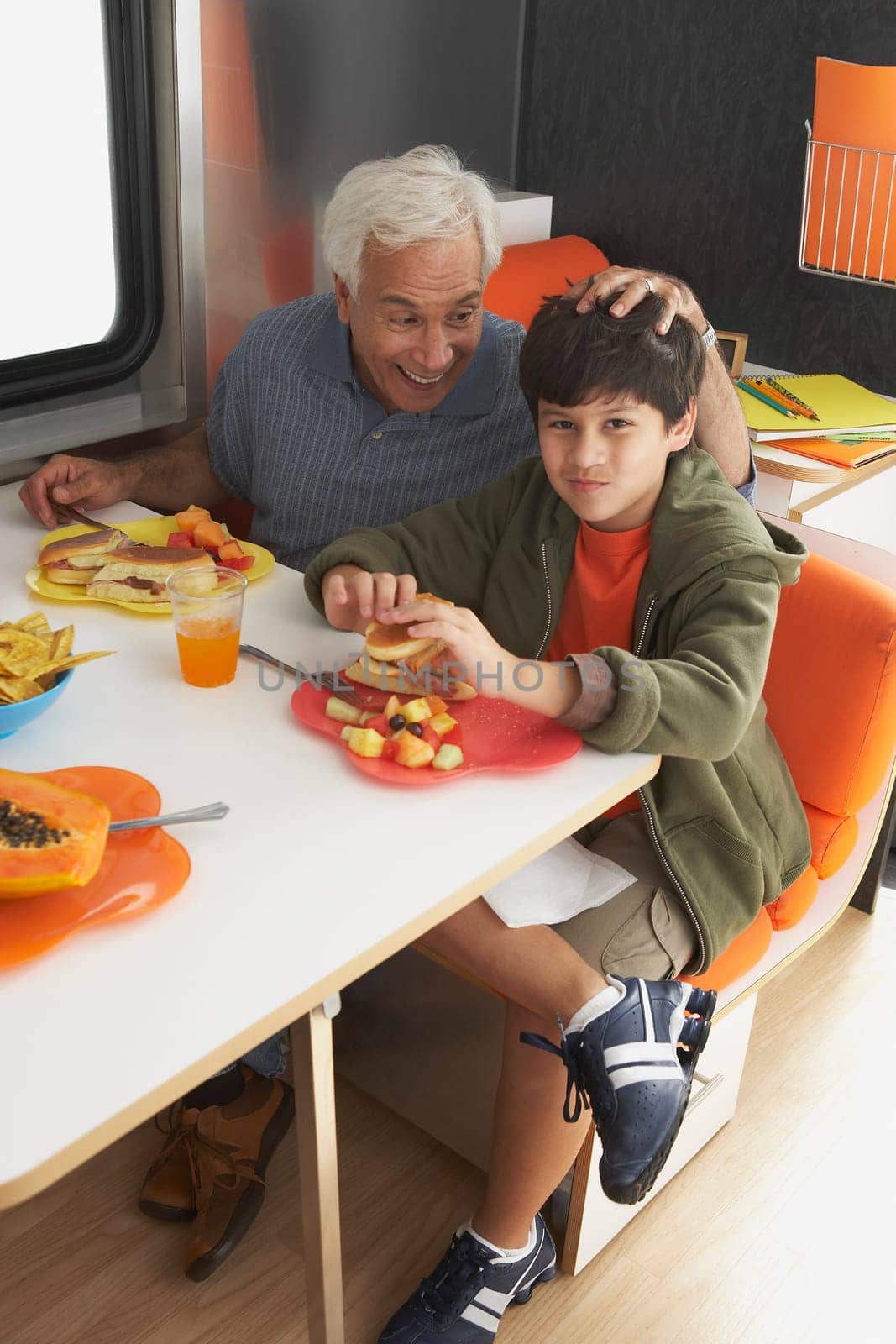 Senior man with his grandson having meal at the dining table