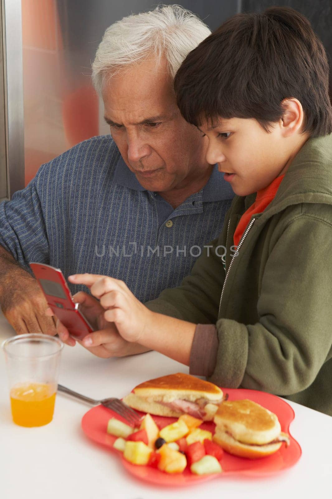 Side profile of a boy teaching his grandfather how to use a mobile phone