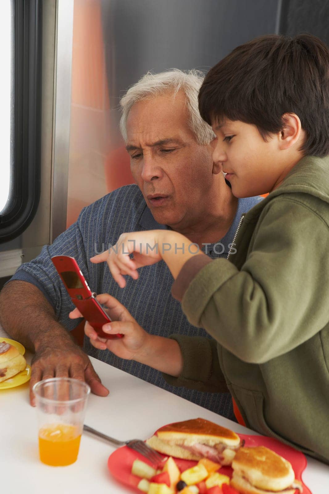 Side profile of a boy teaching his grandfather how to use a mobile phone