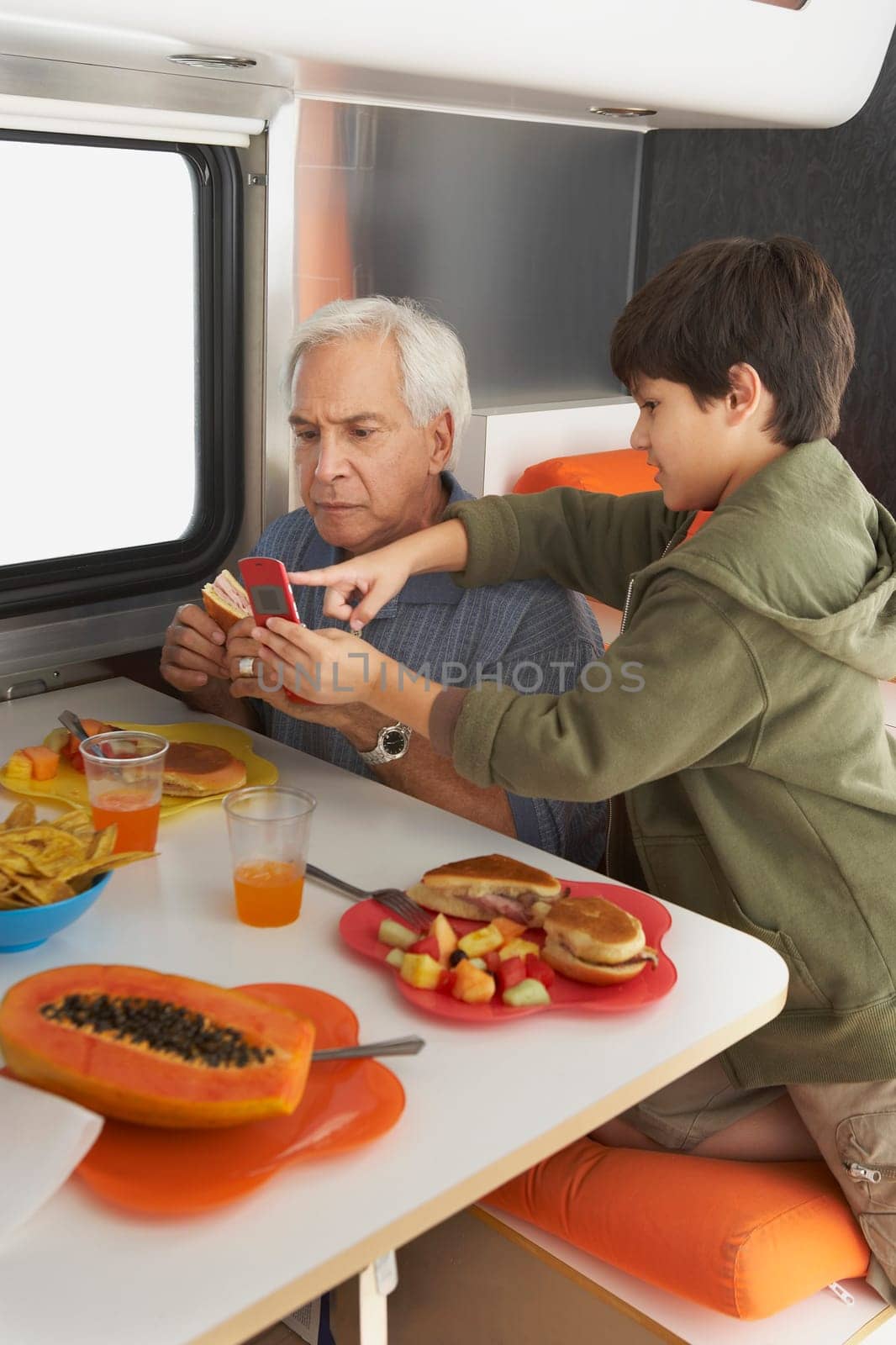 Side profile of a boy teaching his grandfather how to use a mobile phone