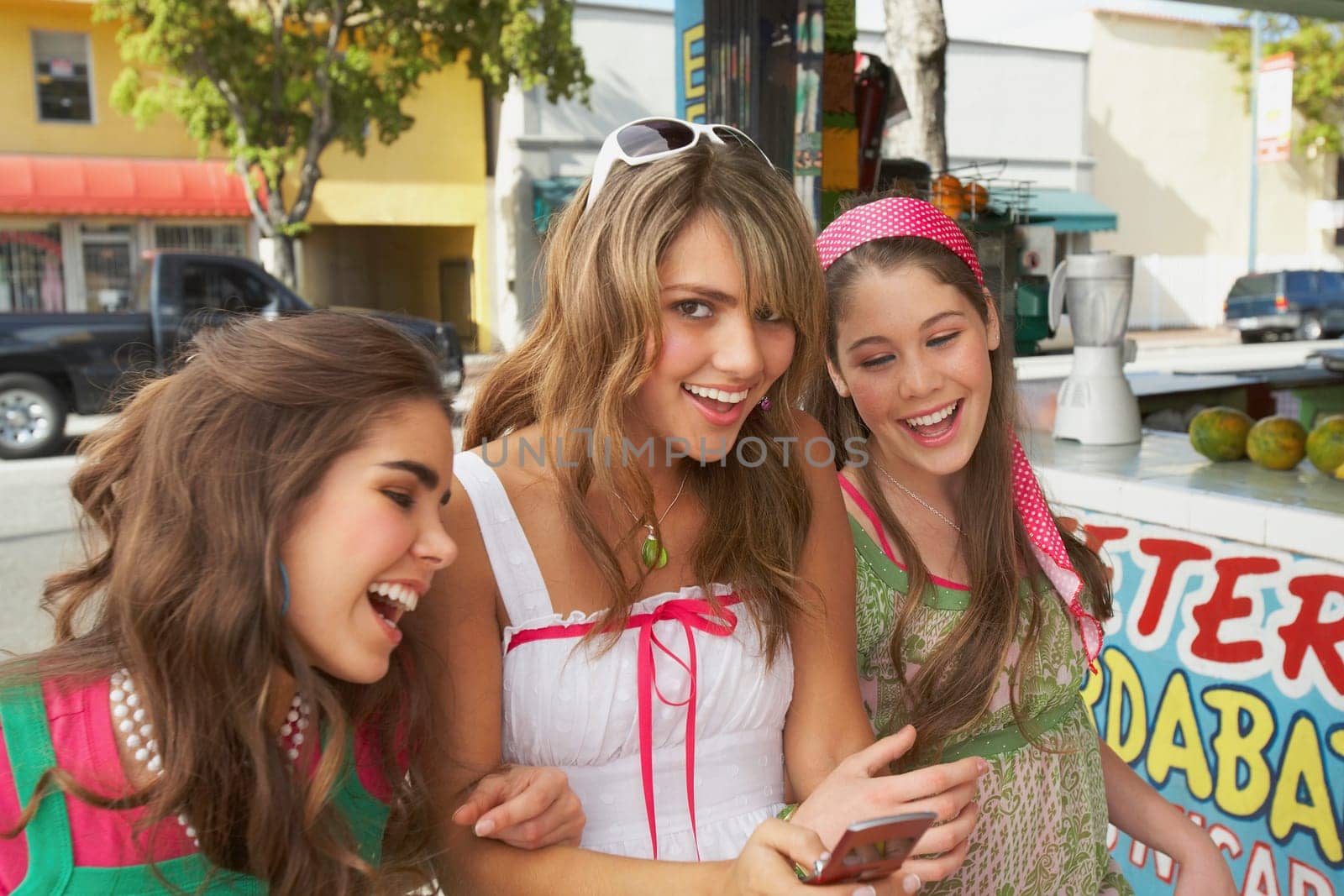Close-up of a teenage girl holding a mobile phone and standing at the juice bar with her friends