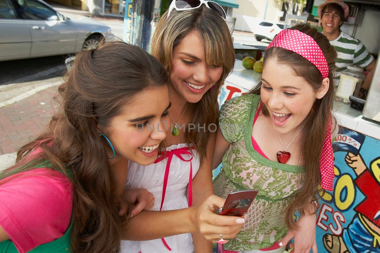 Close-up of a teenage girl holding a mobile phone and smiling with her friends