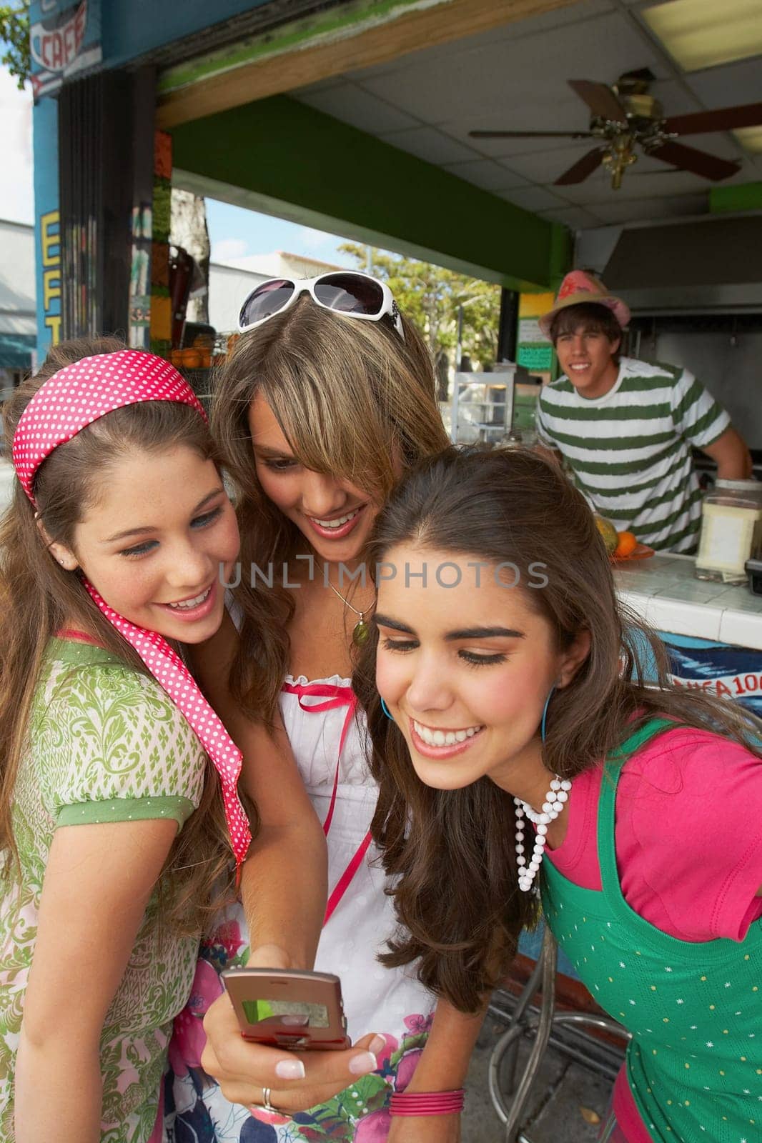 Close-up of a teenage girl holding a mobile phone and standing with her friends