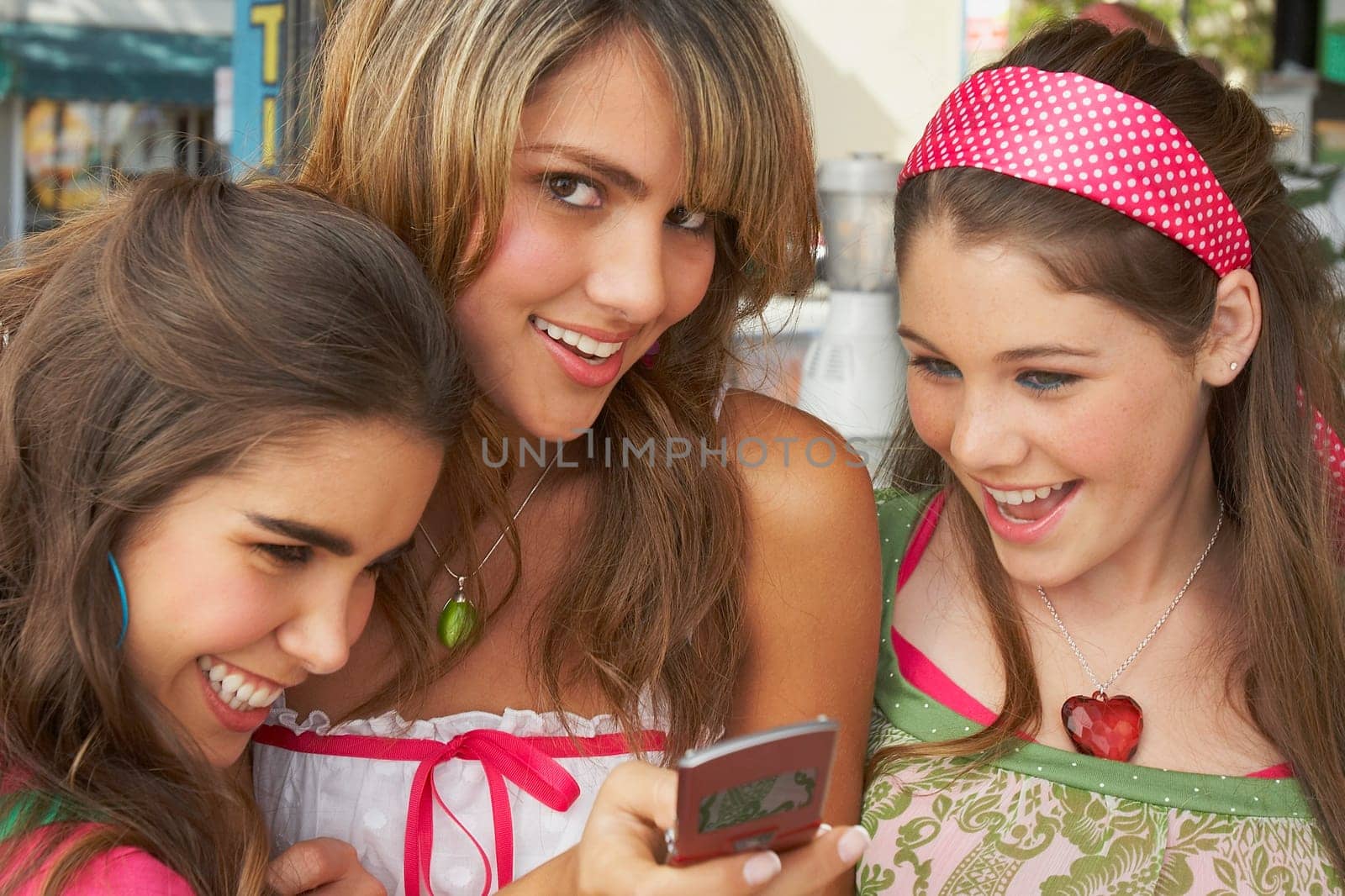 Close-up of a teenage girl holding a mobile phone and smiling with her friends