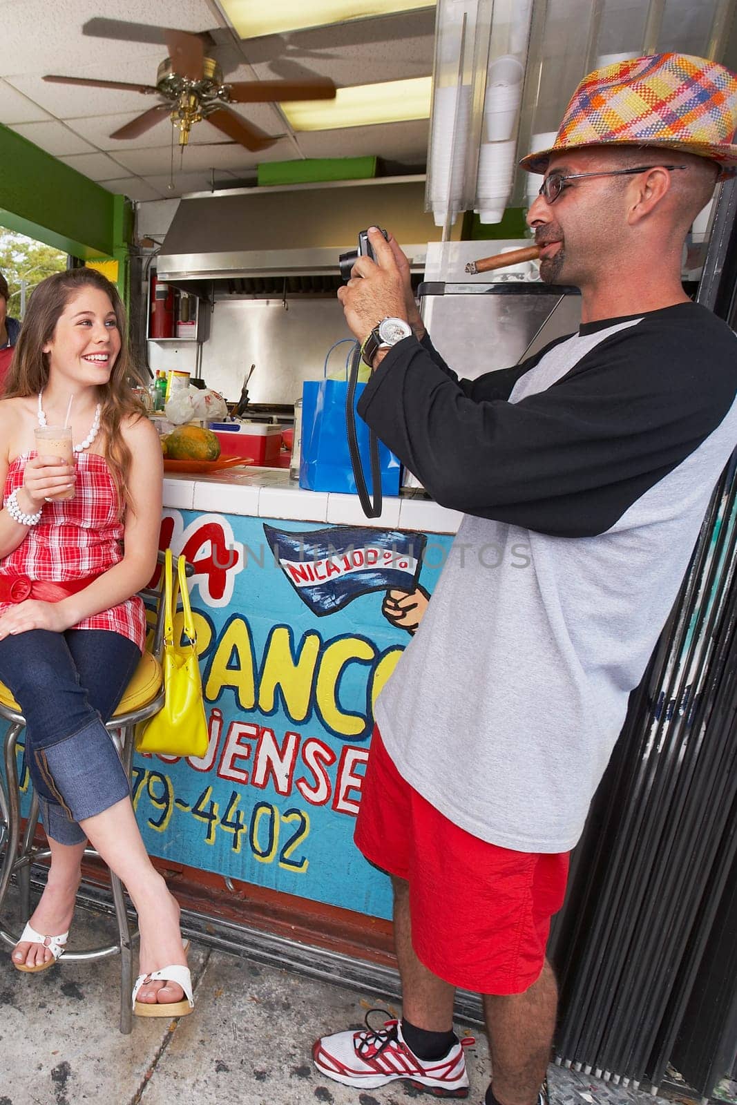 Mid adult man taking a photograph of a teenage girl