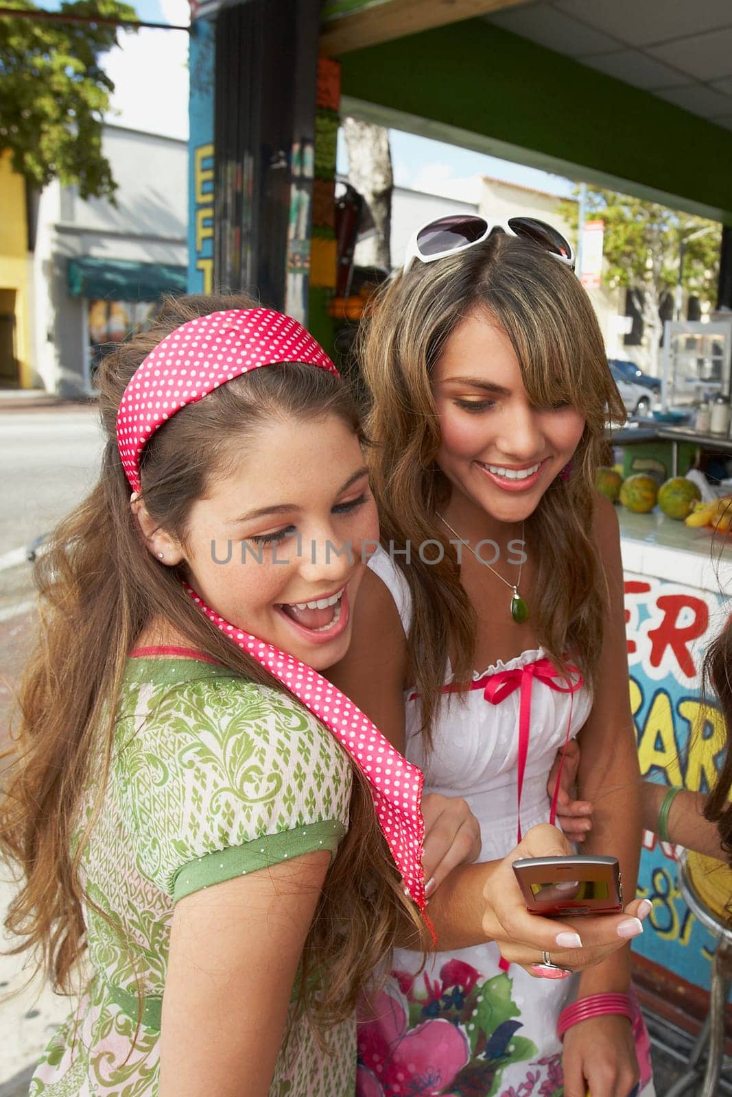 Close-up of a teenage girl holding a mobile phone and standing with her friend