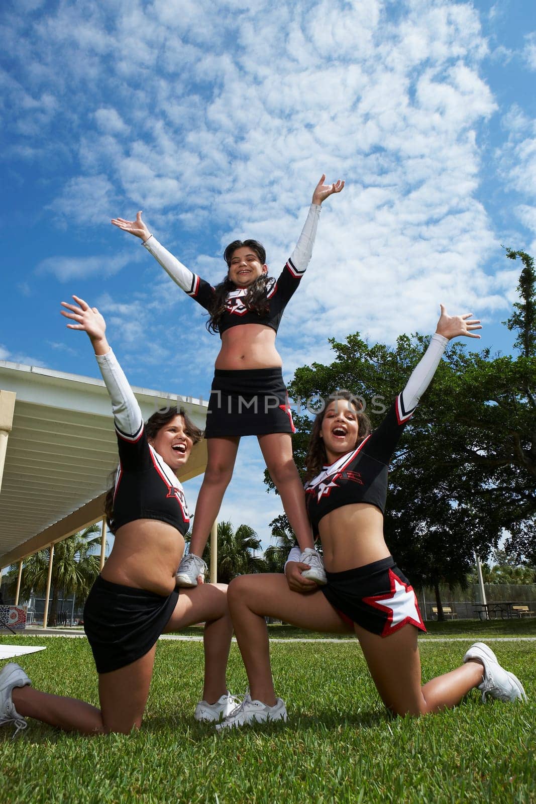 Low angle view of three cheerleaders balancing in a lawn