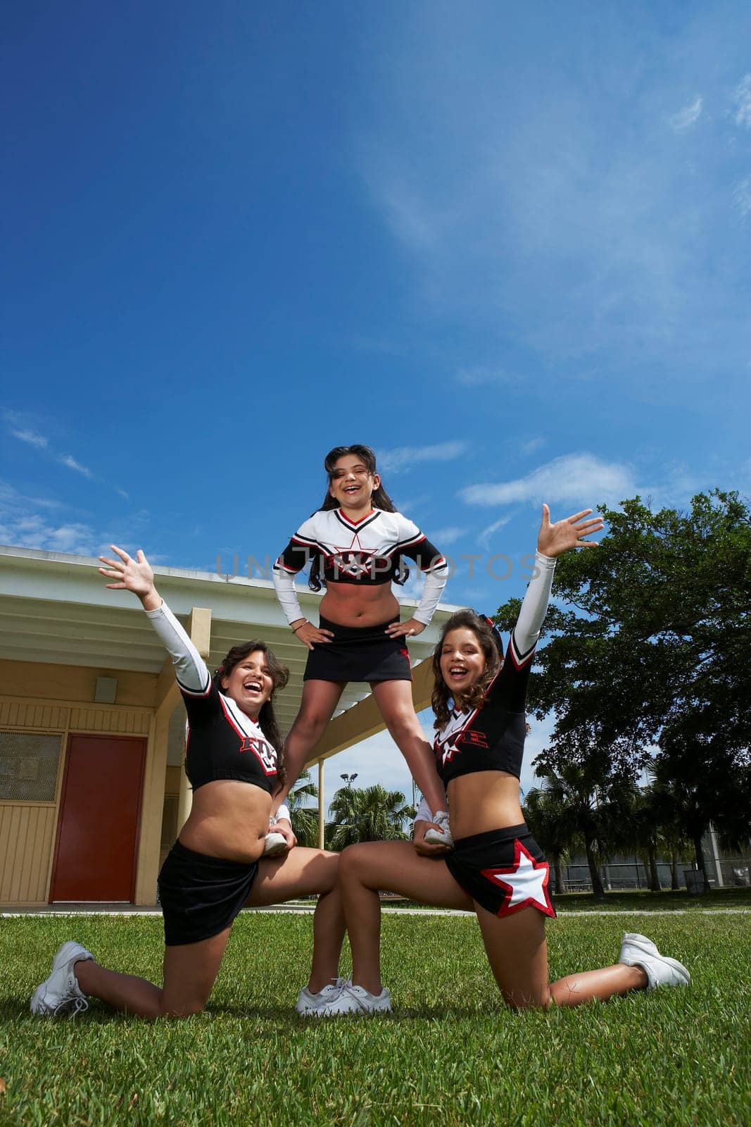 Low angle view of three cheerleaders balancing in a lawn
