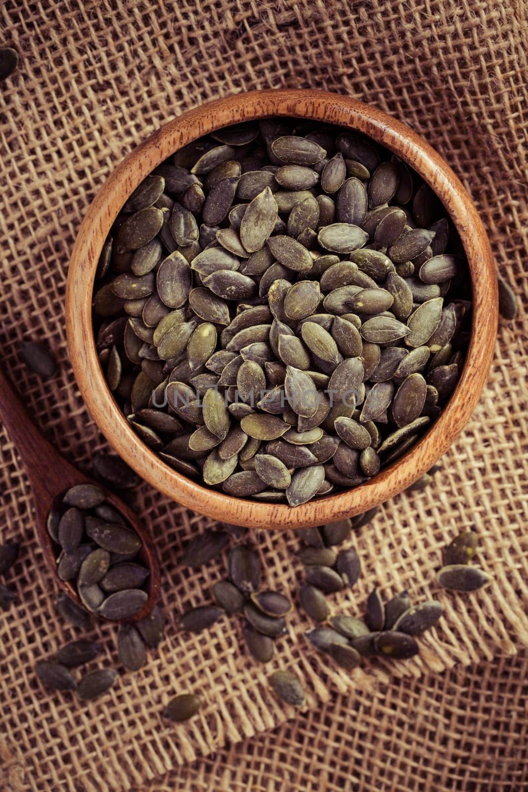 Organic pumpkin seeds in bowl on wooden background
