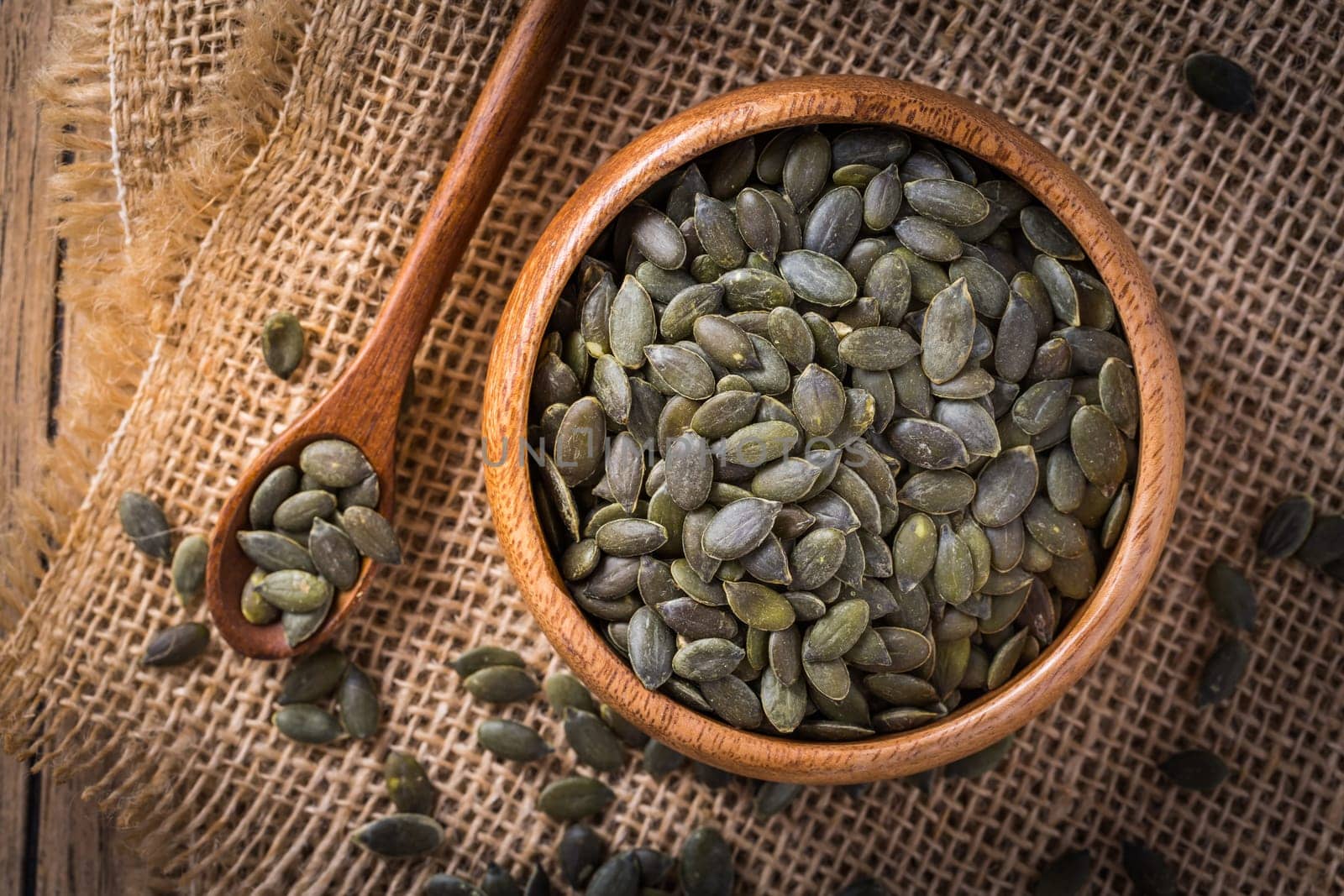 Organic pumpkin seeds in bowl on wooden background