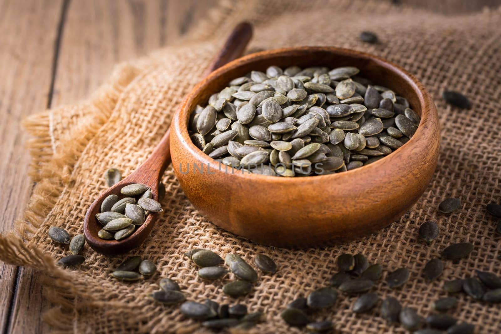 Organic pumpkin seeds in bowl on wooden background